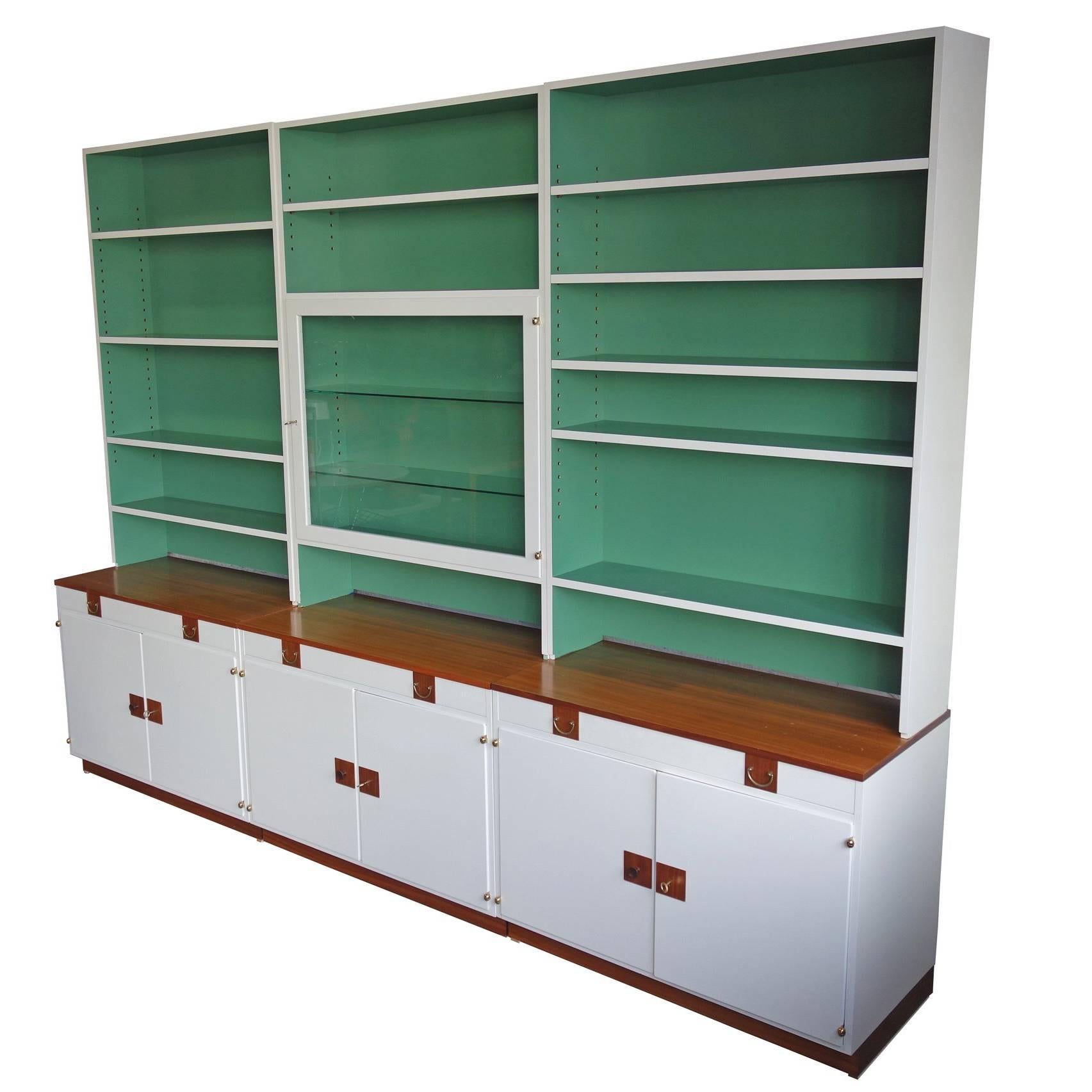 Rarely seen three section wall unit by Josef Frank.

 Featuring two-toned wood pulls with keyed cabinets. White lacquered on a green base and fittings in walnut. The bookcase comes with adjustable shelves and the glass cabinet with two separate