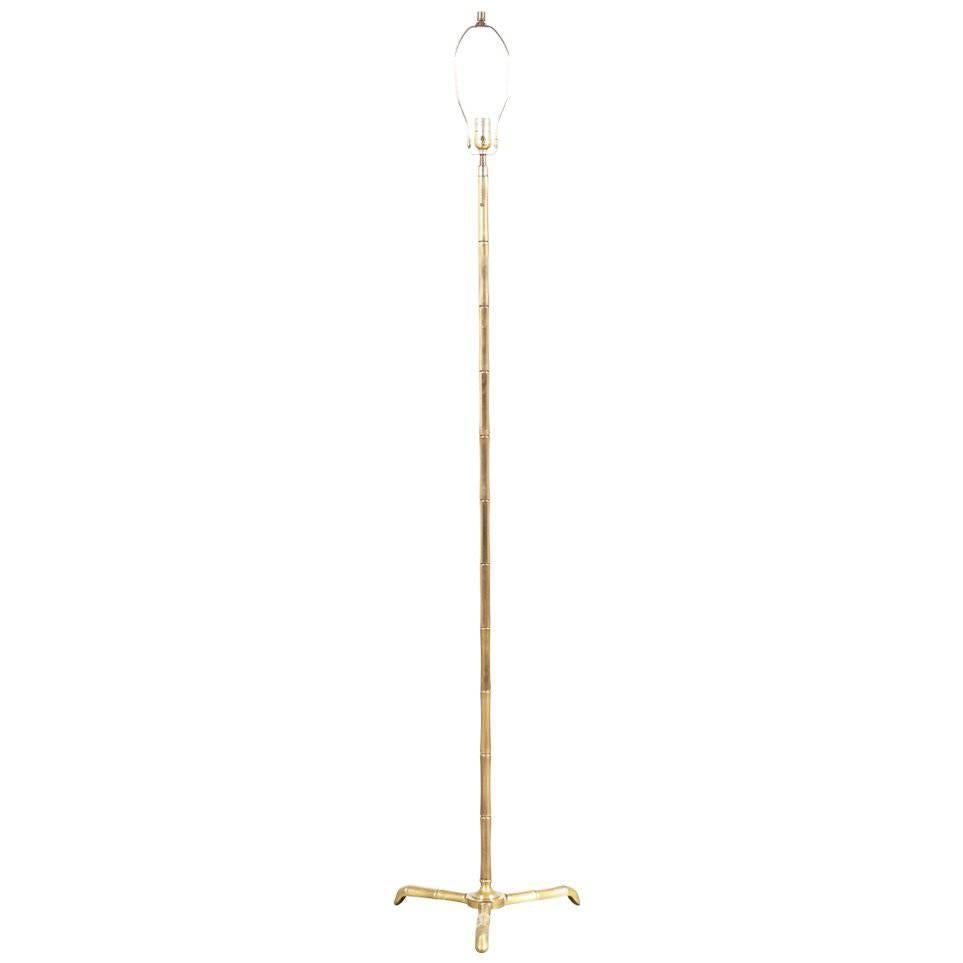 Mid-Century Modern floor lamp designed and manufactured in the United States in the 1900’s. This tripod leg lamp has a sculpted body that resembles bamboo sticks composed of solid brass, showing a lovely age-appropriate patina and minor wear. New
