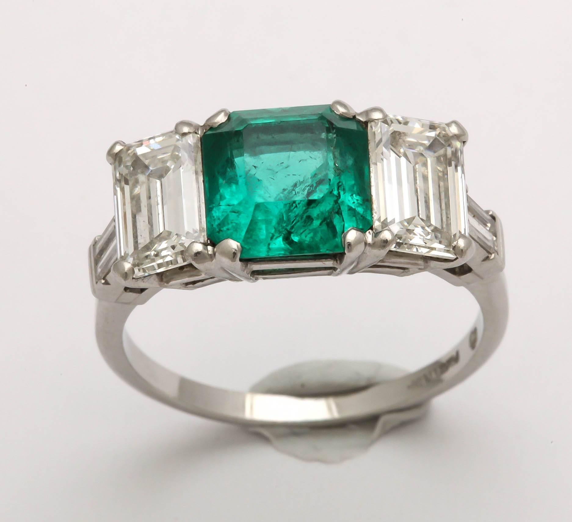 Appraisal Report: A stunning Art Deco ring with a vintage Colombian 2.50-carat medium tone strong saturation Emerald. Flanked by two Emerald 1-carat diamonds VVS/VS color G/H  along with two smaller straight baguettes set in platinum. 
As with most
