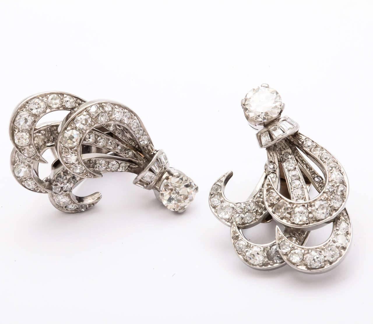 A pair of stunning retro diamond feather form clip earrings set in platinum.
The diamonds are fine quality.  The two larger european cut diamonds weigh 1.20 and the total weight  of the earrings is approximately 3cts.

A UGL appraisal is