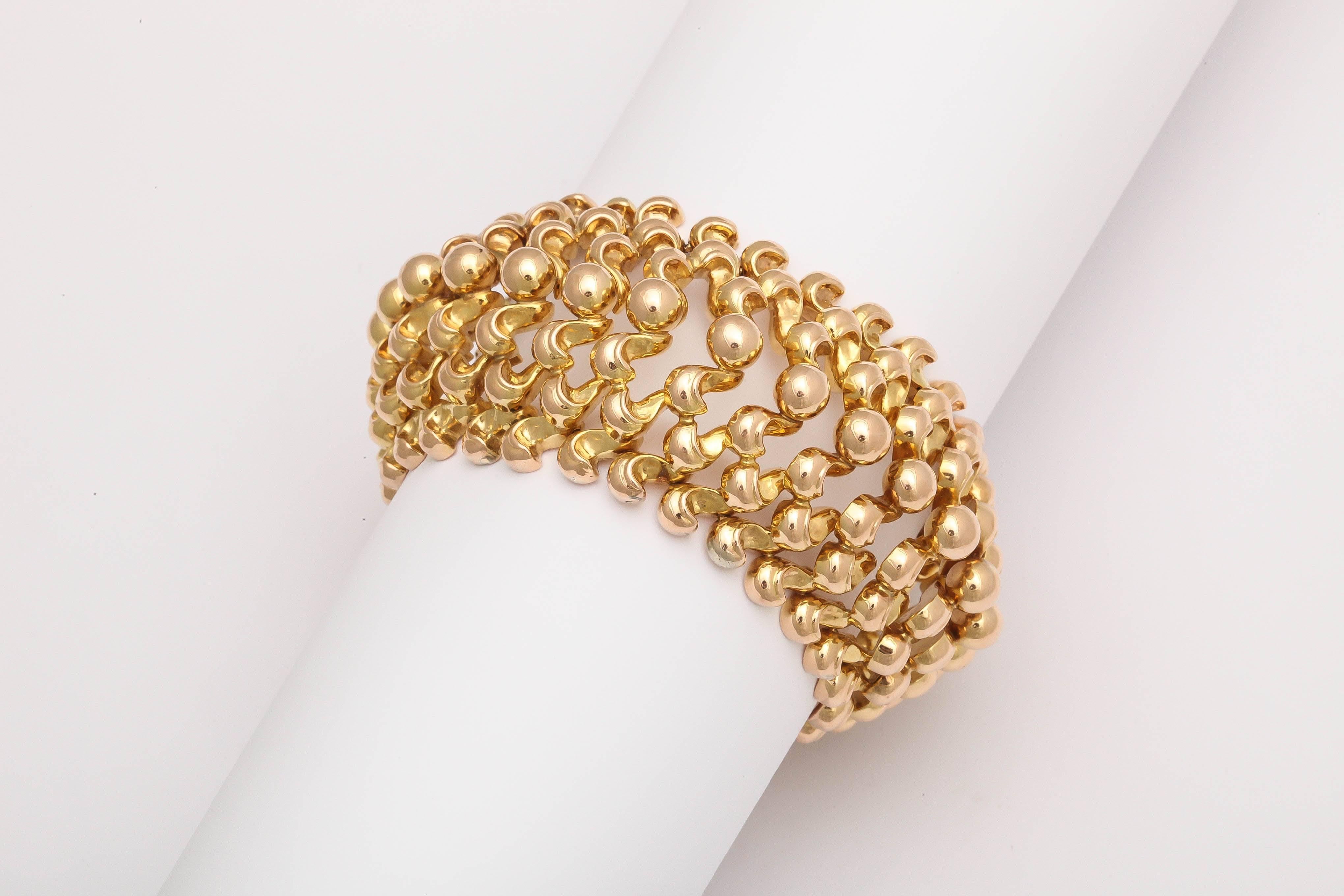 A stunning wide flexible 18-karat retro gold bracelet with center of gold beads  flanked on each side by three rows of cone form beads
The center row is raised which gives the illusion of a cuff.