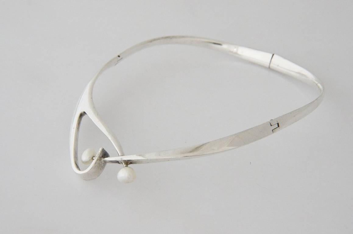 Being offered is a circa 1960 sterling silver and pearl necklace by Sigi Pineda, of Taxco, Mexico, in a modernist design with two (2) fresh pearls. The necklace fastens at the back but is hinged on both sides for easy on off. It measures 15"