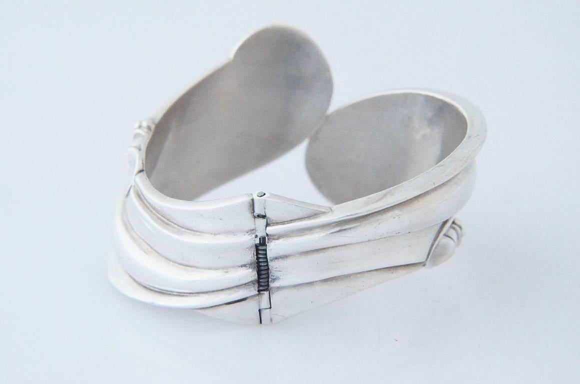 Being offered is a sterling silver hinged clamper bracelet by Margot De Taxco, of Mexico, in a modernistic, architectural motif with planes and many flat and curved surfaces.  It has a wearable length (inside circumference) of 7", where the 2