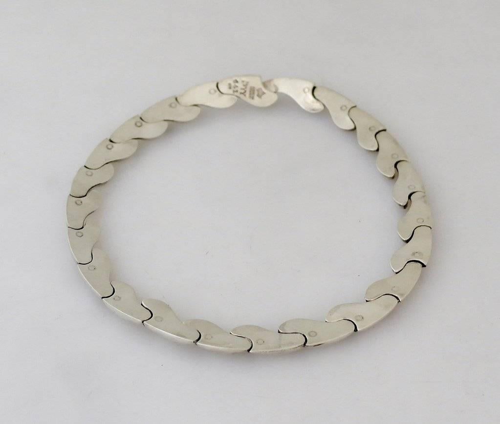 Being offered is a circa 1963 .970 silver necklace by Antonio Pineda of Taxco, Mexico. of modernist design, each wave-like one link masterfully connected.  Lenght 16 1/2 inches.  Weight 3 ozs. (95 grams).  Marked.  In excellent condition.

Stanley