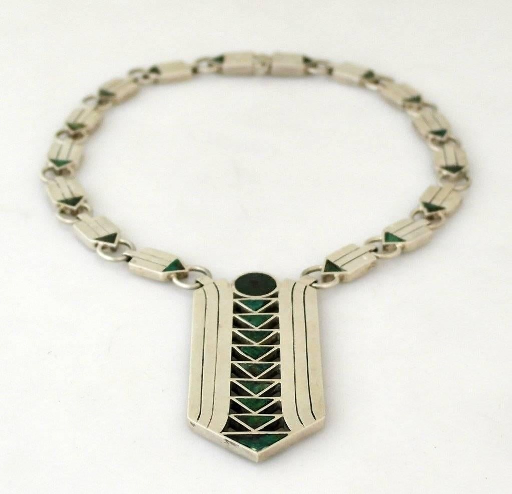 Being offered is a circa 1950 sterling silver and hardstone necklace by William Spratling of Taxco, Mexico, the iconic arrow-form pendant and chain link set with azur-malachite as the arrow points, the pendant 3 1/2 inches long, the rectangular