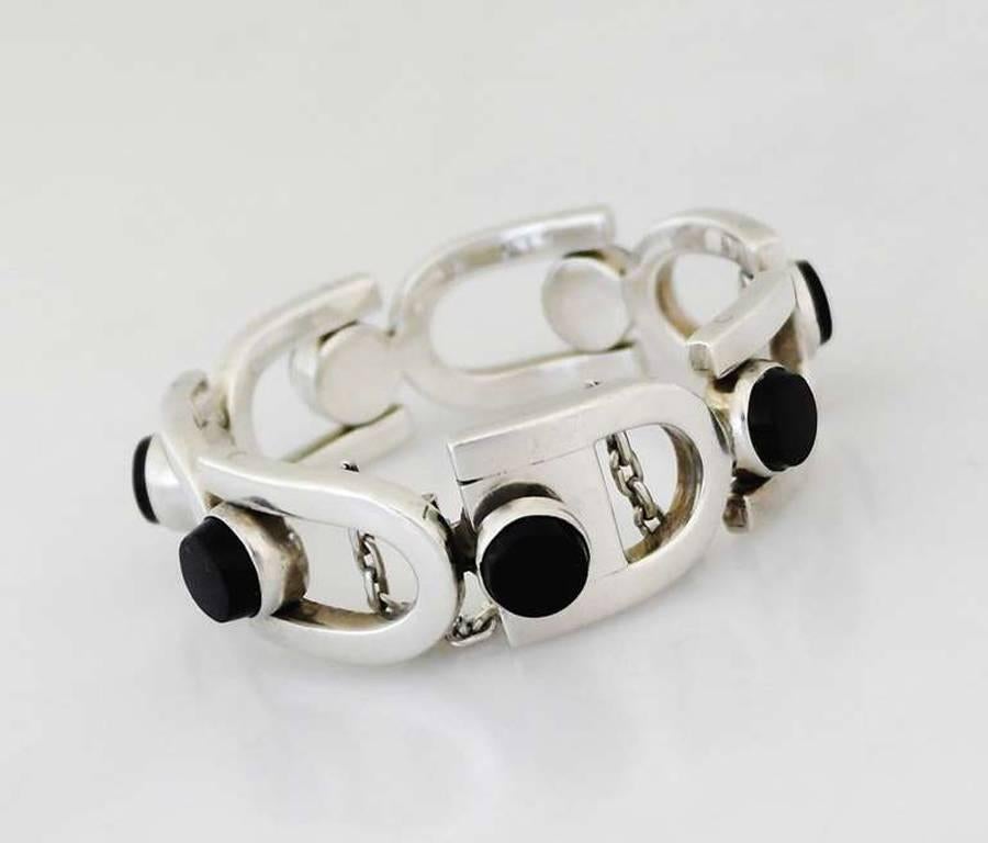 Being offered is a circa 1960 .970 silver and onyx bracelet by Antonio Pineda of Taxco, Mexico. Modernist piece with U-shaped links bearing applied onyx stones; tongue & box closure with security chain. Dimensions: 3/4" wide; inner