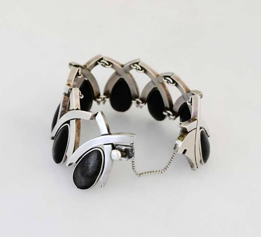 Being offered is a circa 1960s .970 silver bracelet by Antonio Pineda of Taxco, Mexico of modernist design, each 'x' holding a tear shaped piece of onyx.  Dimensions: 1 3/4"; inner dimensions 7". Weight 4 oz. Marked. In excellent