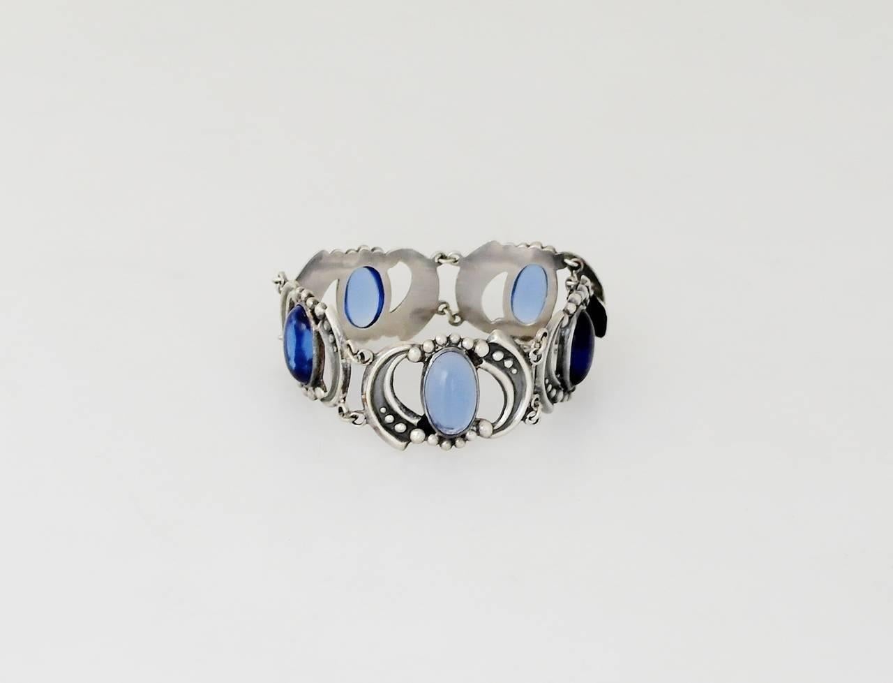 Being offered is a circa 1970 sterling silver bracelet by Los Castillo of Taxco, Mexico; silver bracelet comprising scroll & beaded links with blue glass cabochons. Dimensions: 3/4" wide; inner dimensions 6 3/4". Weight 1.5 oz. Marked