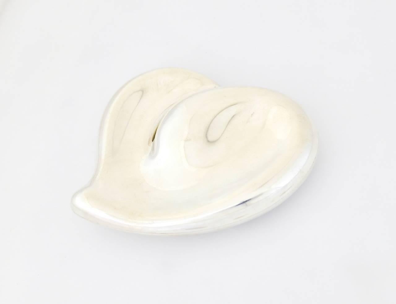 Being offered is a circa 1978 sterling silver belt buckle designed by Elsa Peretti for Tiffany & Co., comprising a figural modernist heart shaped form produced in Italy. Dimensions: 4" x 3 3/4" x 1/2". Marked as illustrated. In
