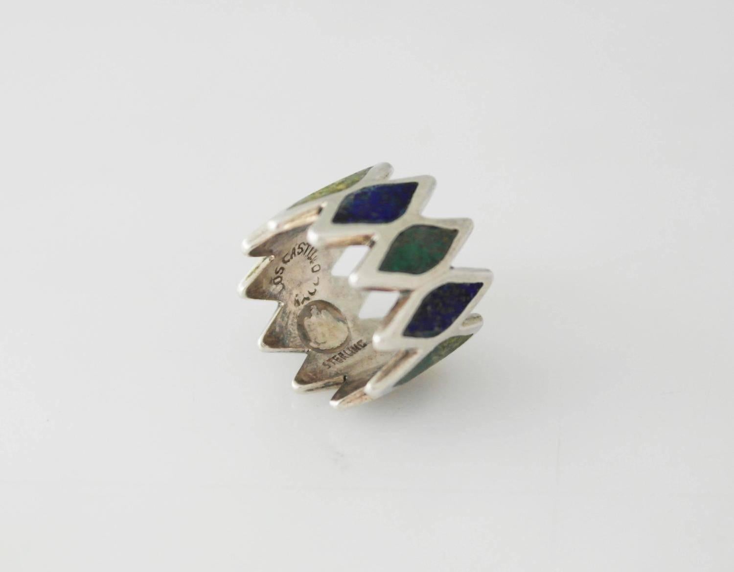 Being offered is a sterling silver ring by Los Castillo of Taxco, Mexico. Handwrought ring comprising diamond motifs with native multi-stone inlay on each diamond. Dimensions: 3/4 inches wide. Size 6. Marked as illustrated. In excellent condition.
