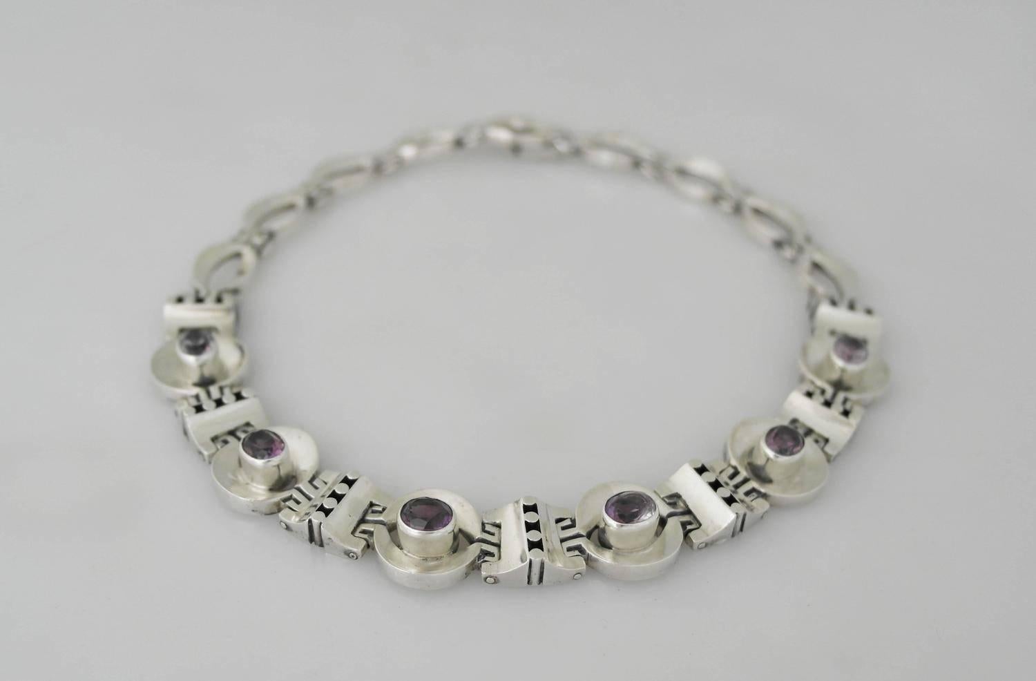 Being offered is a sterling silver necklace made by Los Ballesteros of Taxco, Mexico. Comprising pierced & circular alternating links; six of which have bezel set cabochon amethysts; tongue & box closure. Dimensions: 15 inches x 3/4 inch