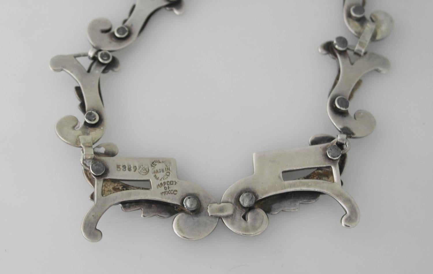 Being offered is a sterling silver bracelet by Margot de Taxco, of Taxco, Mexico. Attractive piece with a silver leaf motif & enameled scroll on each link; tongue & box closure. Dimensions: 15 inches x 1 3/4 inches at its widest. Marked as