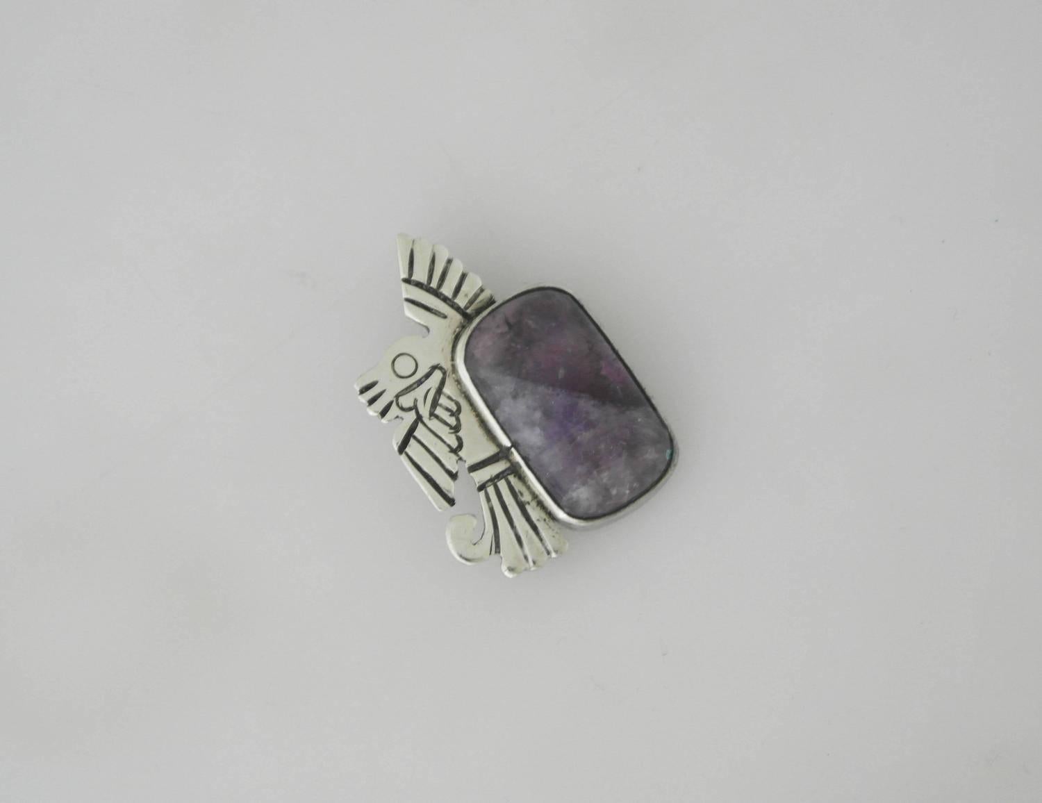 Being offered is a sterling silver brooch made by William Spratling of Taxco, Mexico. Made during Spratling's first design period (1931-1946). Pin of a silver eagle with incised detail alongside a large cabochon amethyst. A matching brooch is