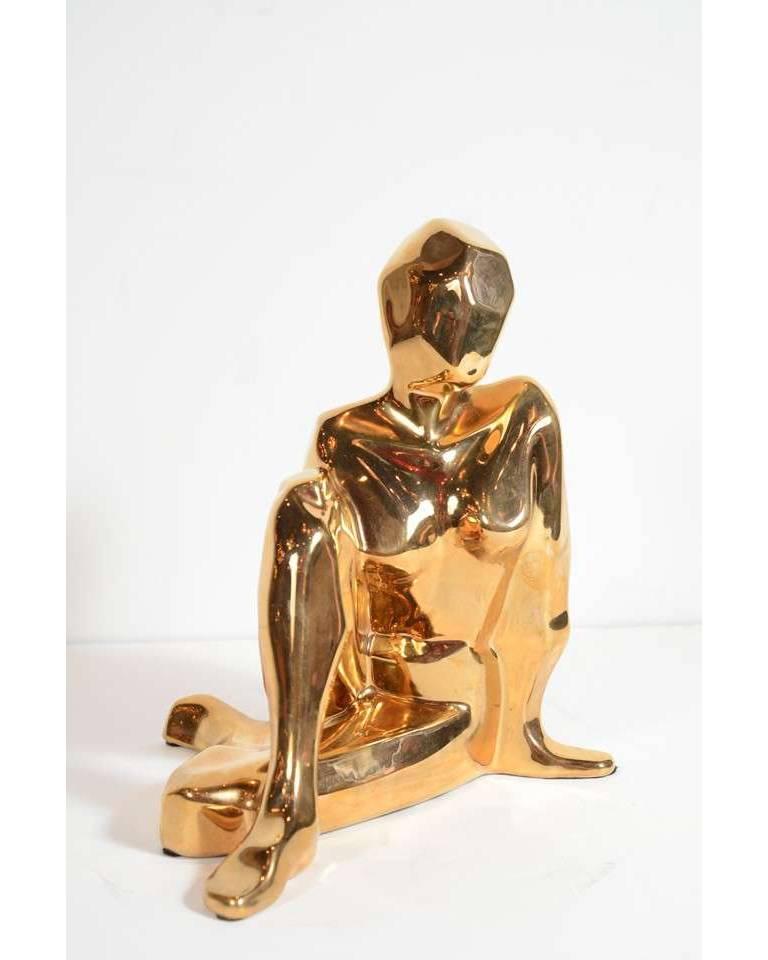 This gold-plated ceramic sculpture features a crouching figurative female sculpture with stylized Cubist form. With its radiant glaze and dynamic form, this is not only a stunning piece of Mid Century Modern design element but a timeless sculpture,