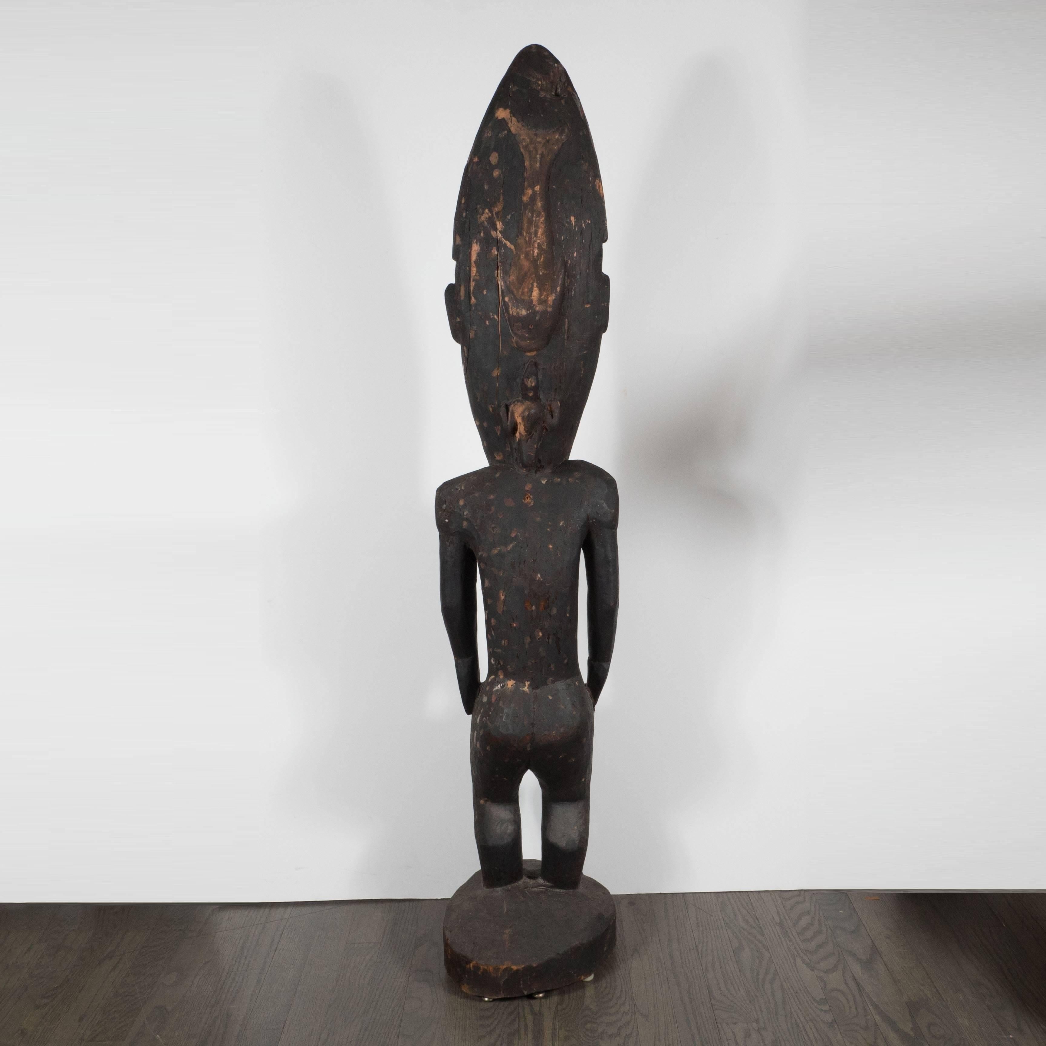 Realized in Papua New Guinea towards the end of the 19th Century, this is a striking example of tribal sculptures from the region. The oversized ovoid head has inset circular eyes rendered in white pigment. Traces of organic pigment have been