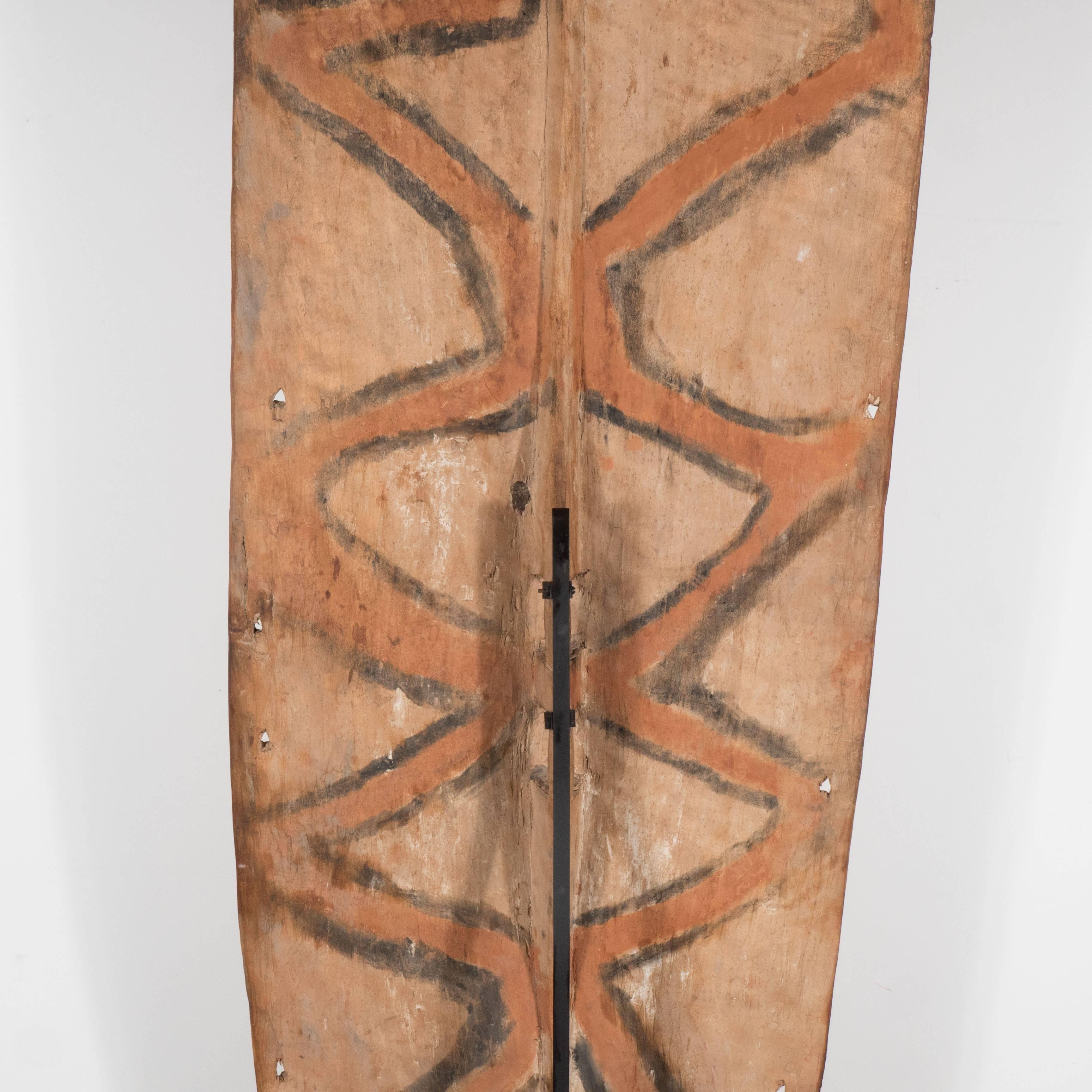 Dieses markante Schild wurde gegen Ende des 19. Jahrhunderts in Papua-Neuguinea hergestellt. Die rechteckige Form aus unbehandeltem, nubukfarbenem Hartholz ist mit weißen, geschwungenen und geometrischen Mustern beschriftet. Eine kleine geschnitzte