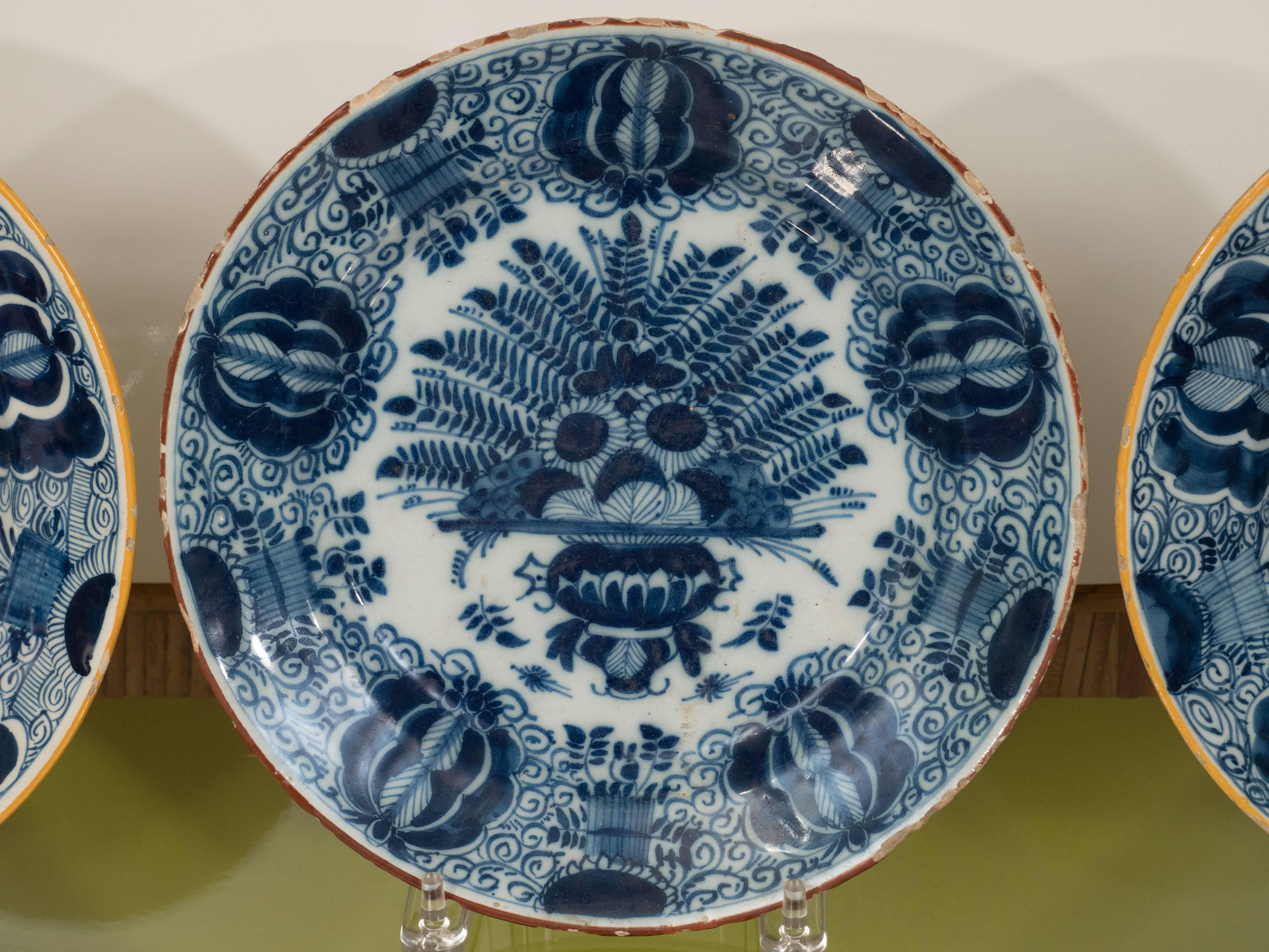 A series of three Dutch delft blue and white chargers hand-painted in a stunning deep blue with a yellow rim. The hand-painted design is known as the 
