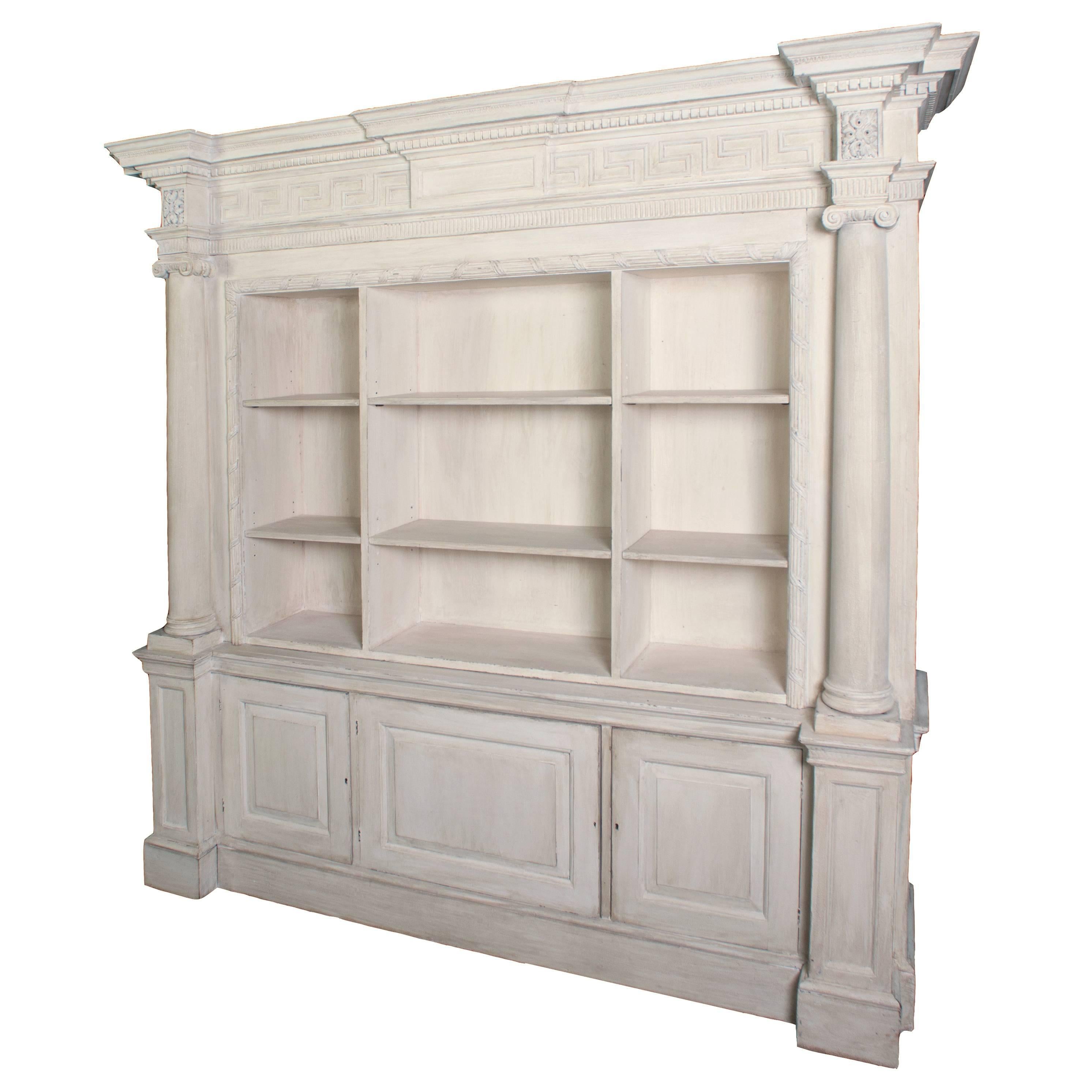 A cream painted wooden neoclassical bookcase in two sections