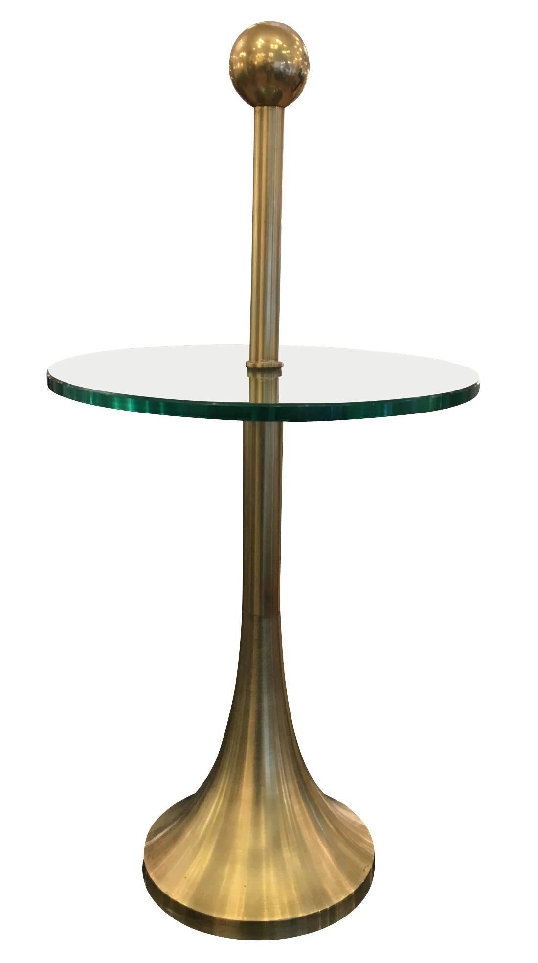Curvy lines characterize this side table which was originally finished with a dark bronze patina. The trumpet shaped base ends with a sphere at the top. The thick glass at the center has straight edges. It can be polished upon request to bring out