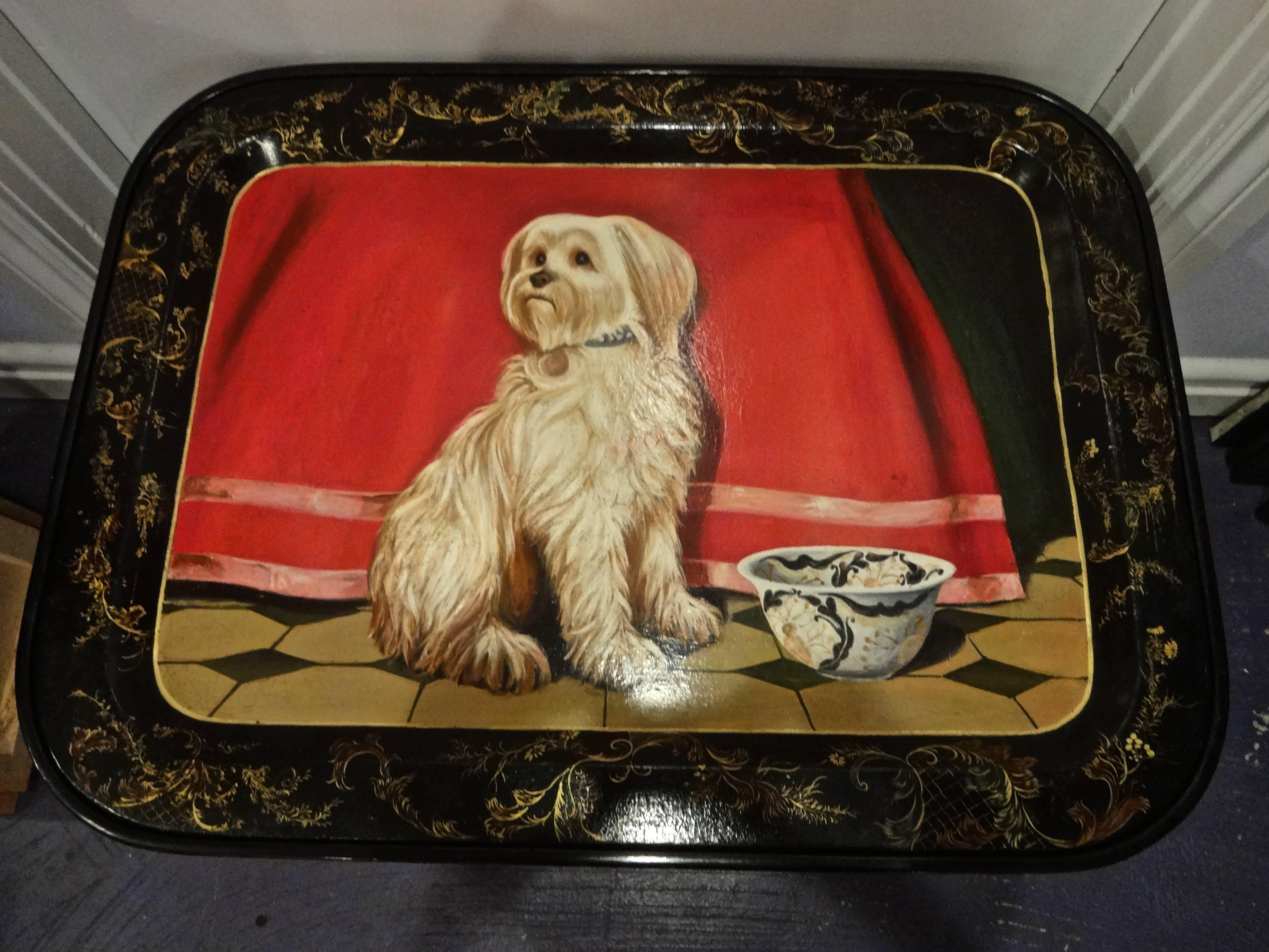An English Victorian hand painted rectangular lacquered papier mache tray depicting a Lhasa Apso dog and bowl with patterned border, fitted to a custom black faux bamboo base with gold accents, joined by an x-form stretcher.