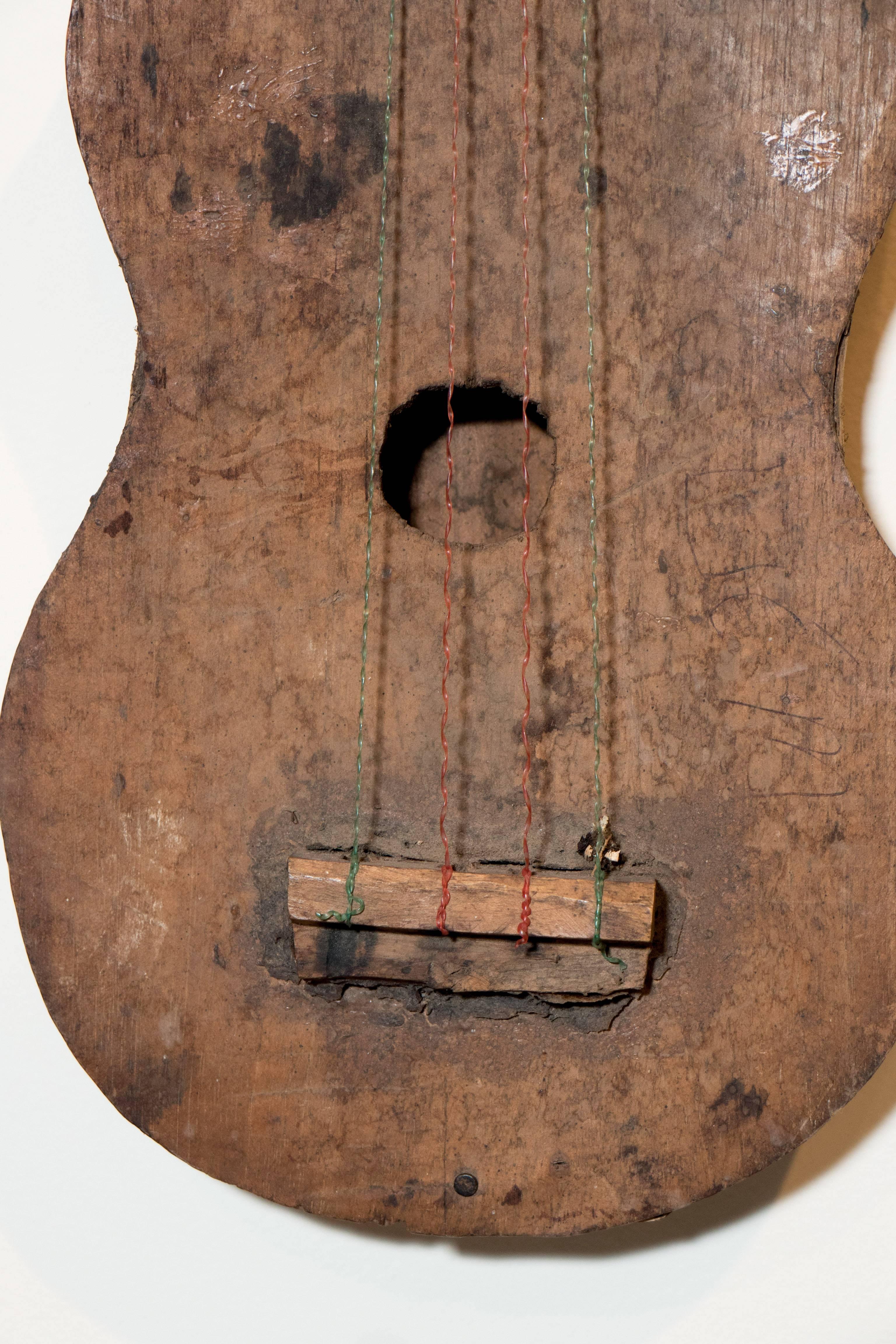 An antique primitive hand carved and constructed wooden folk art violin, showing many years of use. An unusual and striking wall or shelf piece.