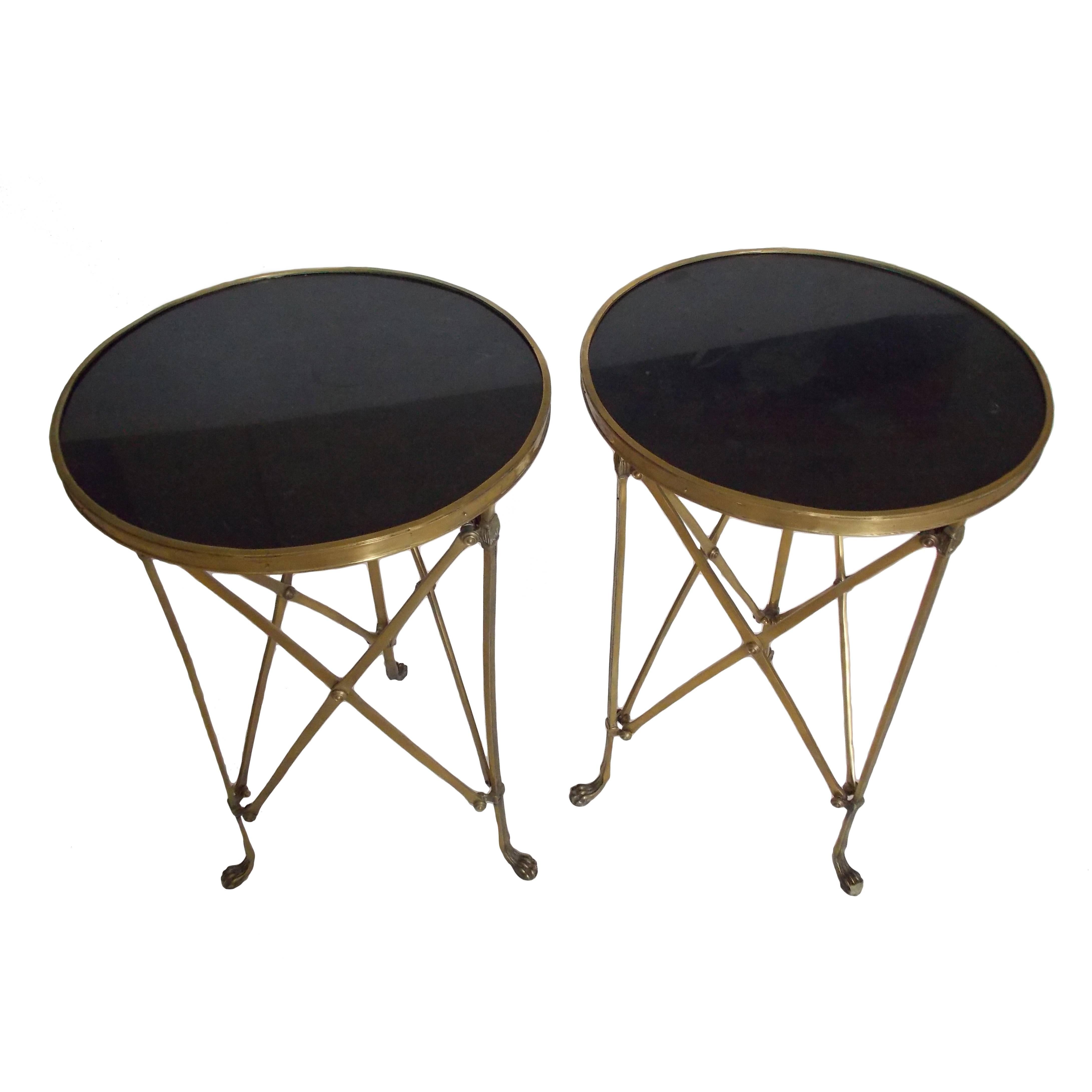 A stunning Mid-Century pair of French gueridon tables with black granite tops.
The brass bases have vertical cross stretchers joined by a medallion in the center and rest upon cat paw feet.