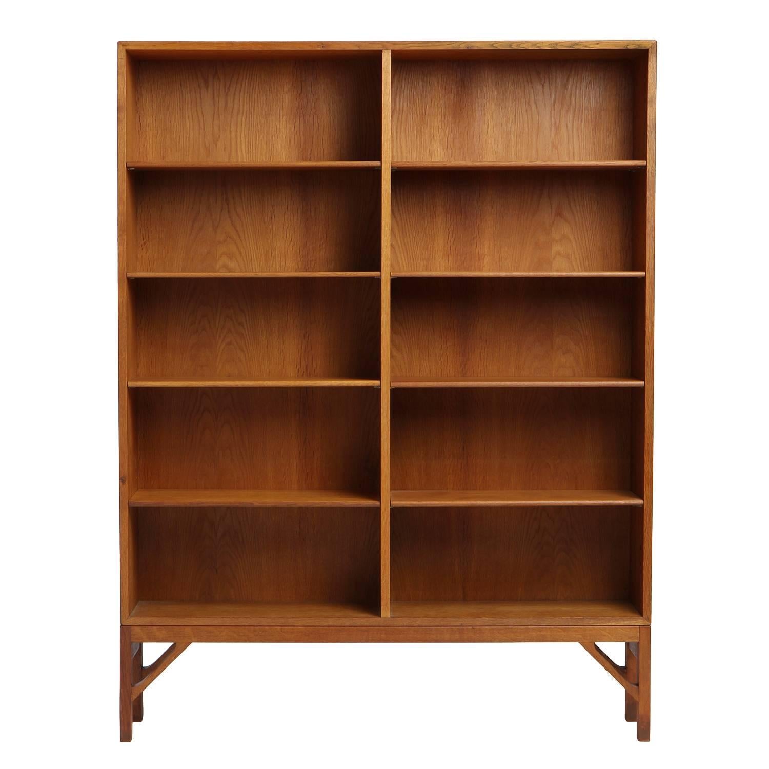 A spare and elegant Scandinavian Modern standing bookshelf / bookcase designed by Borge Mogensen. Unit is constructed in solid active-grained oakwood with adjustable shelves and an architectural base with trussed supports. Made in Denmark, circa