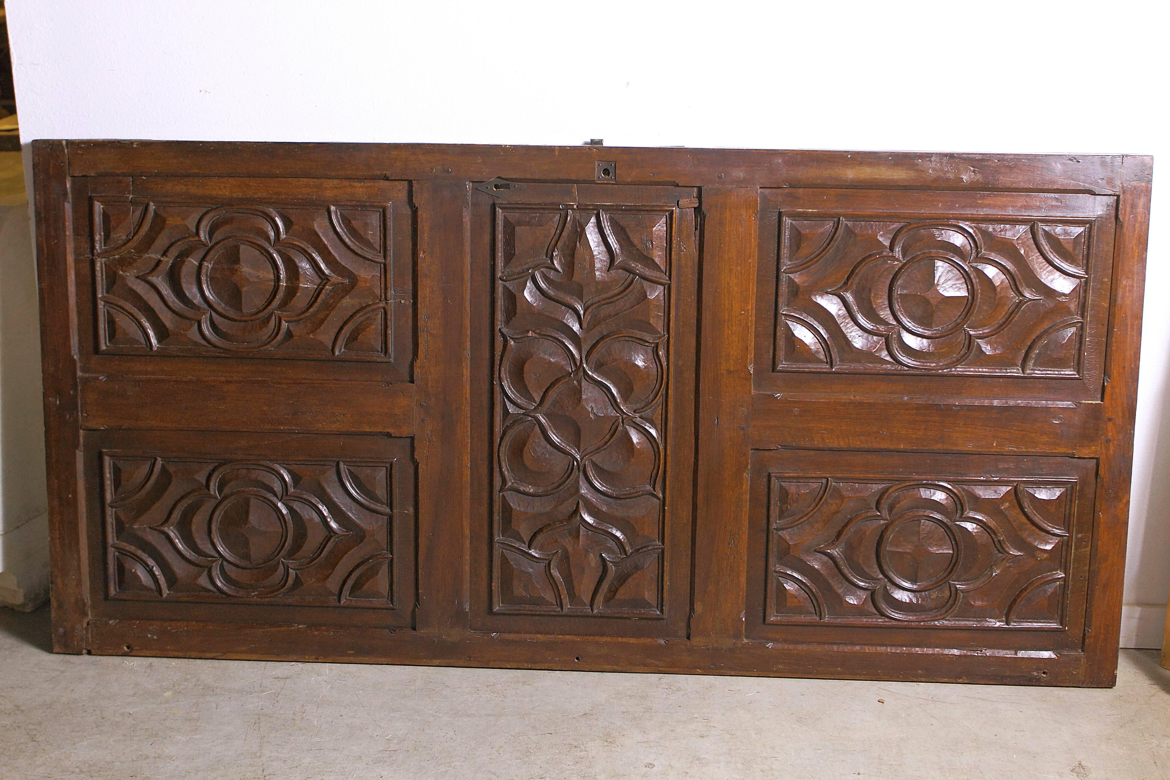 This bold walnut wood door from the 1600’s is from the area of Languedoc, in southern France. The hand carved, raised, beveled motifs are Gothic quatrefoil and cinquefoil cusps. The carving is deep and shows flawless hand carved shapes. There are