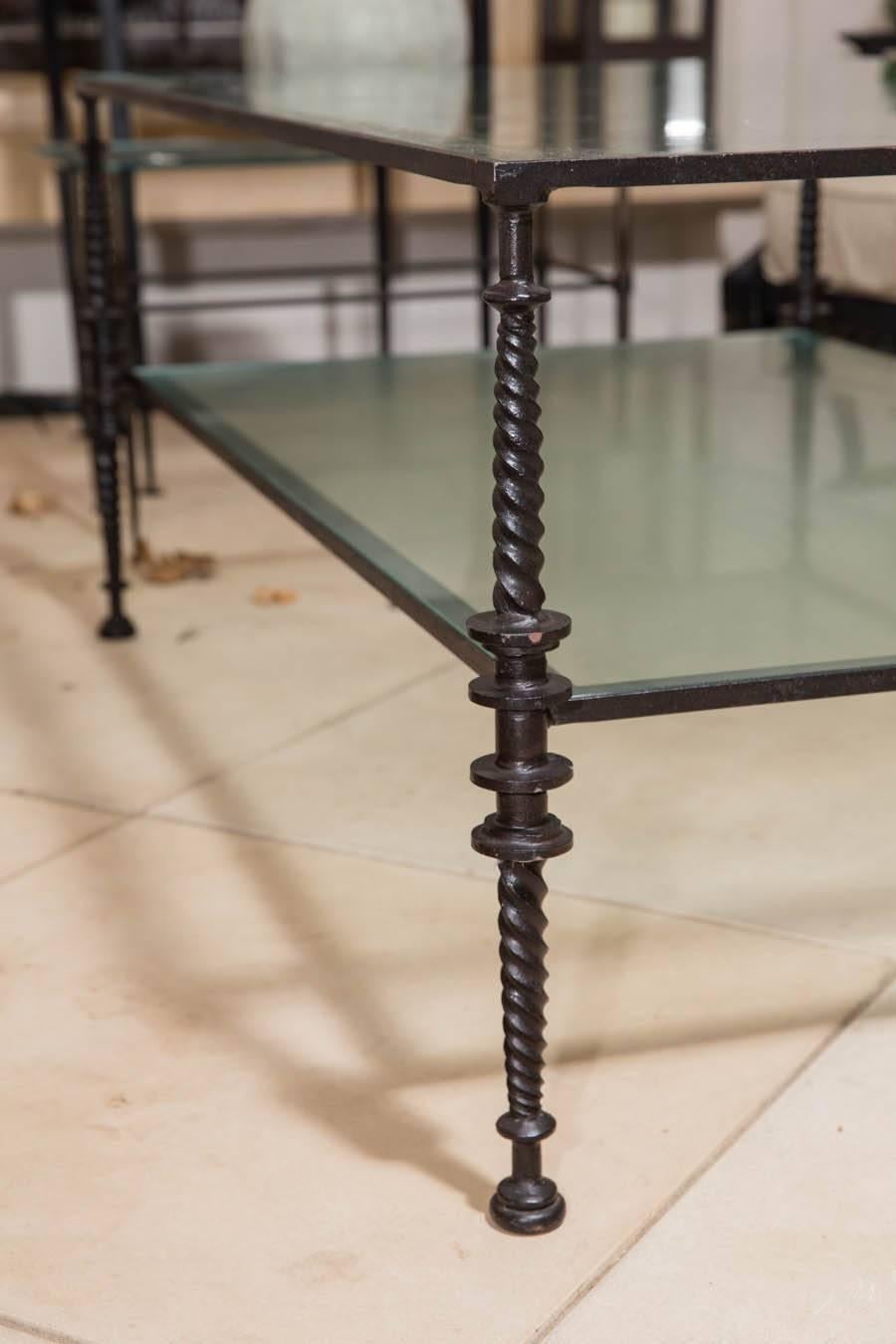 Giacometti style black wrought iron and glass two-tier cocktail table.