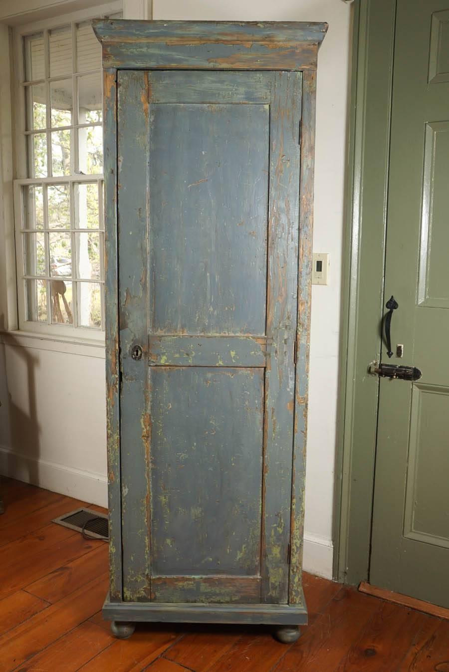 This original painted grey/green one door cupboard has original hardware with lock and keep. The wear on the paint is perfect and the size is not massive. The bun feet give it character and inside you will find three shelves.