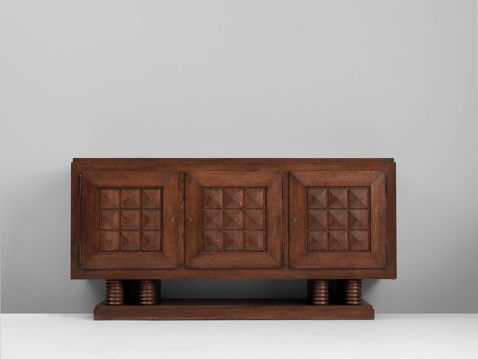 Credenza, in stained oak, by Gaston Poisson, France 1930s.

Sturdy credenza in oak with graphical doorpanels and parquet top. This three-door sideboard is equipped with several shelves and drawers which provide plenty of storage space. The shelves