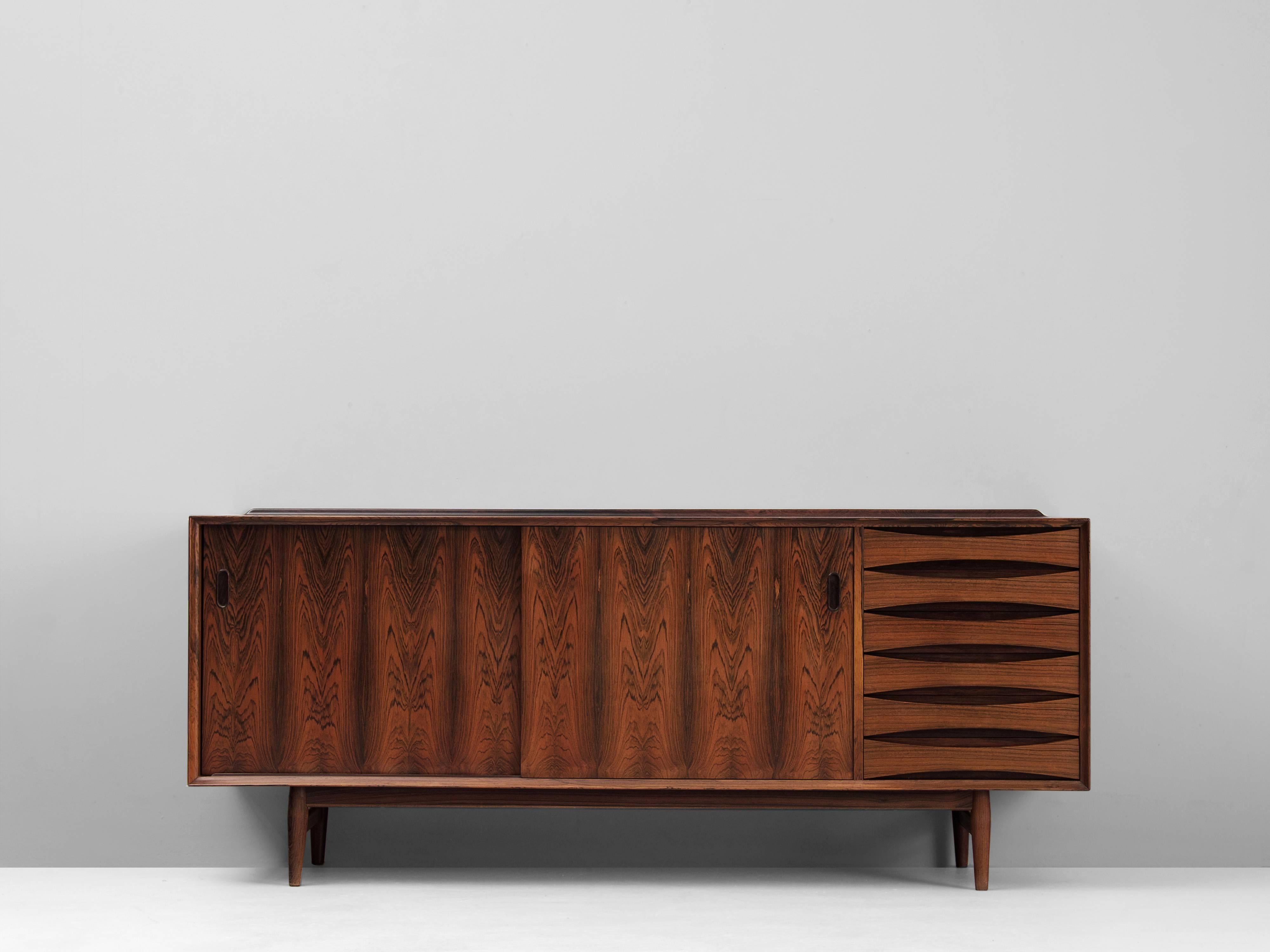 Sideboard model OS 29, in rosewood, by Arne Vodder, Denmark, 1958.

High quality credenza in rosewood. Well designed sideboard with two sliding doors and six concave shaped drawers. At the back of the top, a solid rosewood raised edge is made