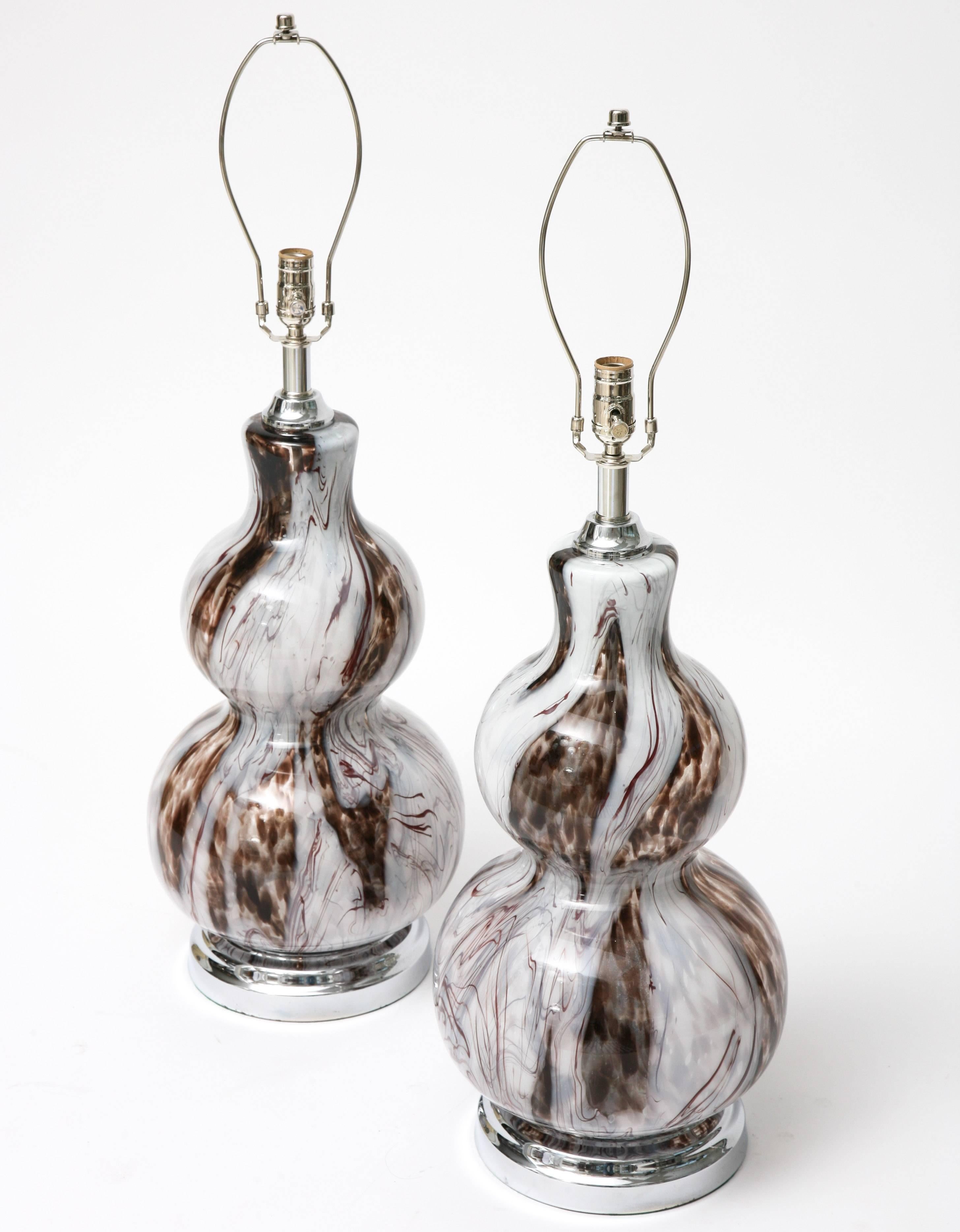 This spectacular, large-scale pair of table lamps date for the 1970s and are fabricated with Murano glass, gourd-shaped bases with polished chrome base and sockets.
 
The Murano glass is translucent in colors of clear, off-white and root-beer