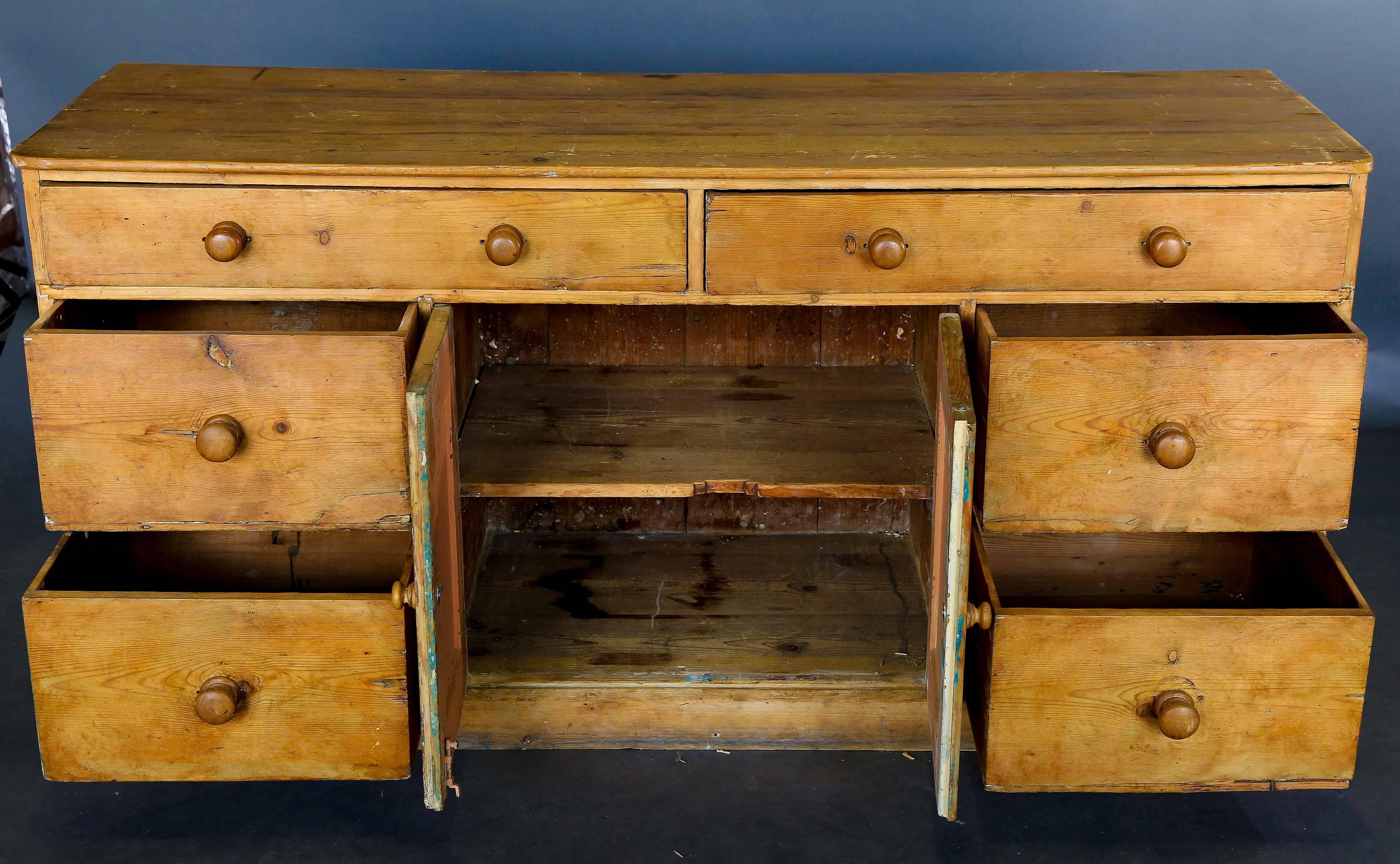 Victorian scrubbed pine dresser base with two long drawers above two cupboard doors flanked by four drawers, raised on a plinth base.