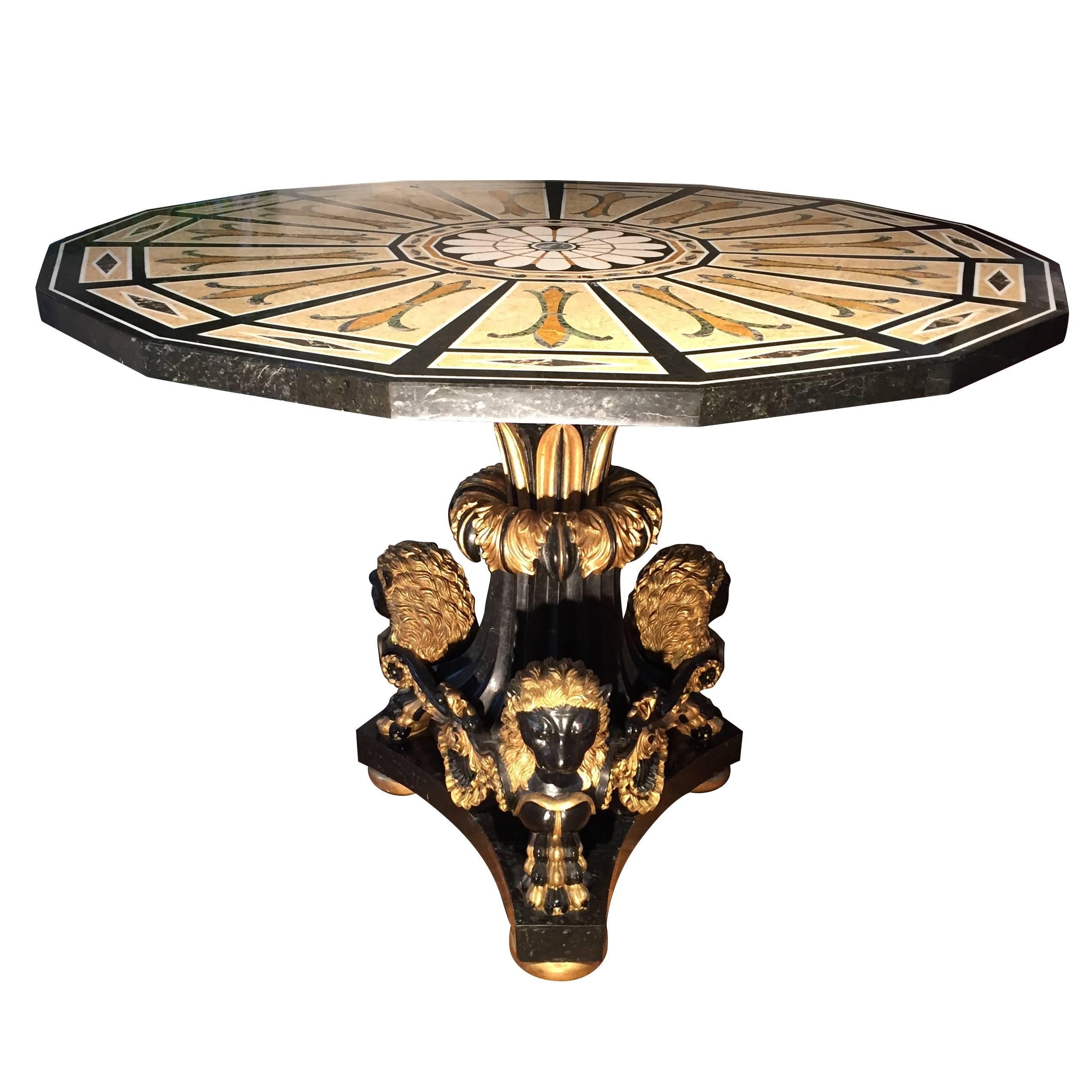 The top of this Pieta Dura Marble Table consists of multiple specimen of marble in ochre, beige and green tones contrasted by outlines in black Onyx and white marble. The base too is veneered in black marble with exception of the gilt Lion Heads and