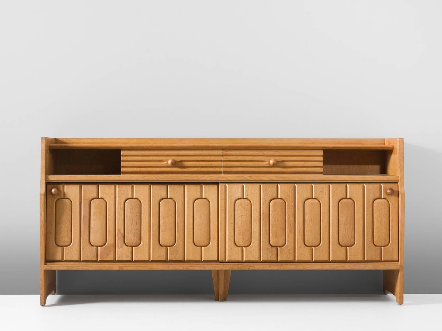 Sideboard, in oak and ceramic, by Guillerme et Chambron, France, 1960s.

Credenza in oak by French designers Guillerme & Chambron. This sideboard is equipped with two sliding-doors and a set of drawers. The front of the sideboard is beautifully