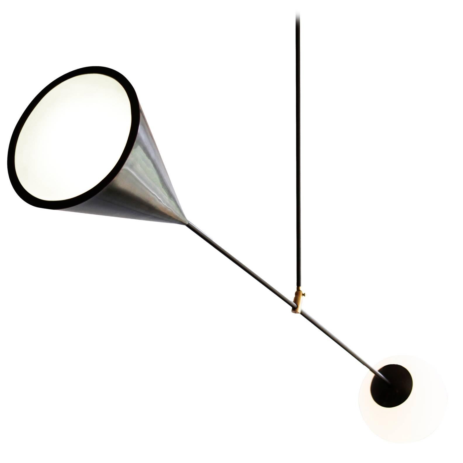 A conical light source at one end and a handblown matte white glass orb on the other hold this piece in balance. The central hinge mechanism allows adjustment of the fixture to any desired angle.

Available in satin black (a rich warm black) and