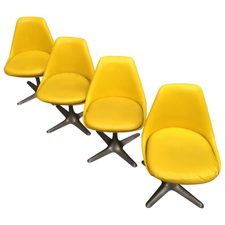 Four yellow leather upholstered dining chairs.