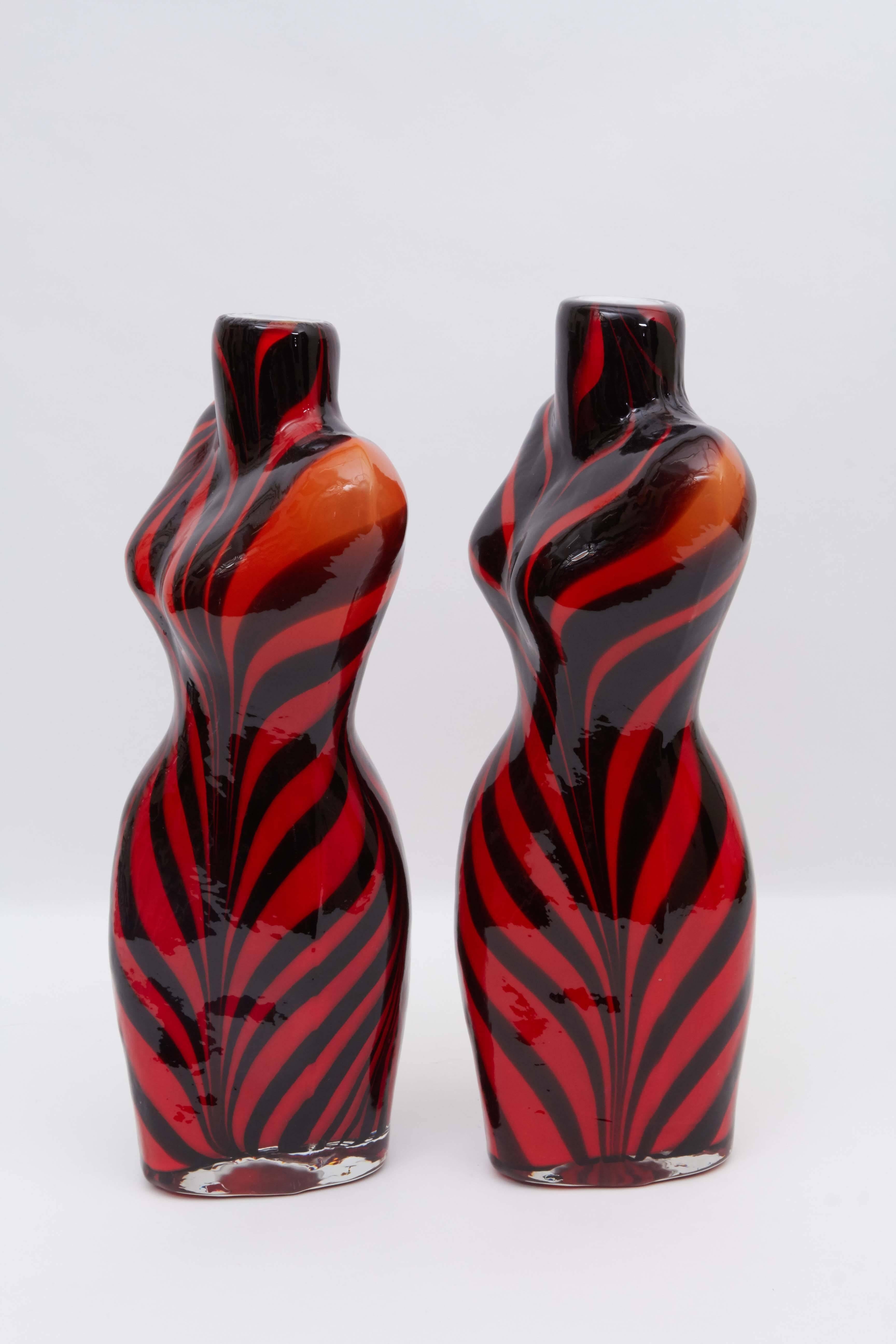 A pair of Italian, handblown Murano glass sculptural vases, produced, circa 1980s, each artfully crafted into the form of a female torso, with black and red tiger stripes, cased within a clear layer, with white interior. Very good condition, wear to