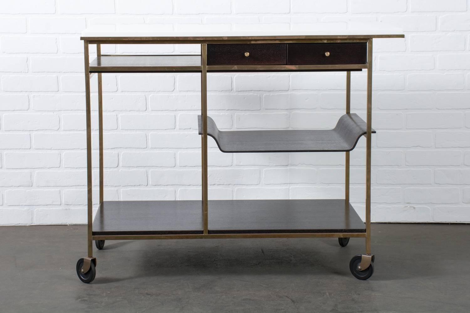 This rare Mid-Century Modern tea/bar cart was designed by Paul McCobb for the Irwin Collection by Calvin, Grand Rapids, USA, circa 1950s. It features a solid brass frame that rests on four casters; dark mahogany shelves, drawers and a removable