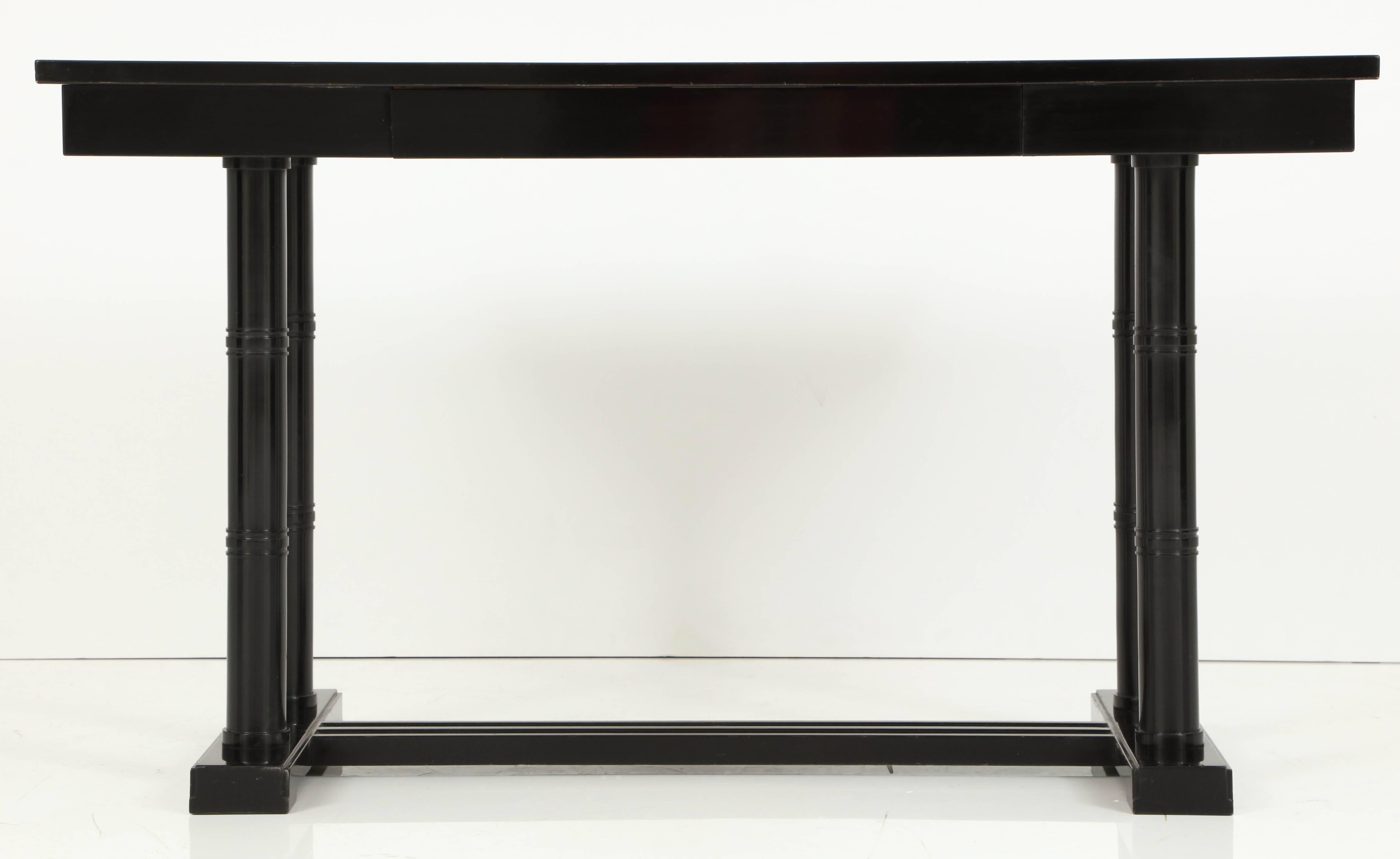A Swedish Art Deco writing table, circa 1920s, the book matched figured elm top with an ebonized border, above a conforming frieze with a single drawer, raised circular turned and banded supports joined by an H-form base.