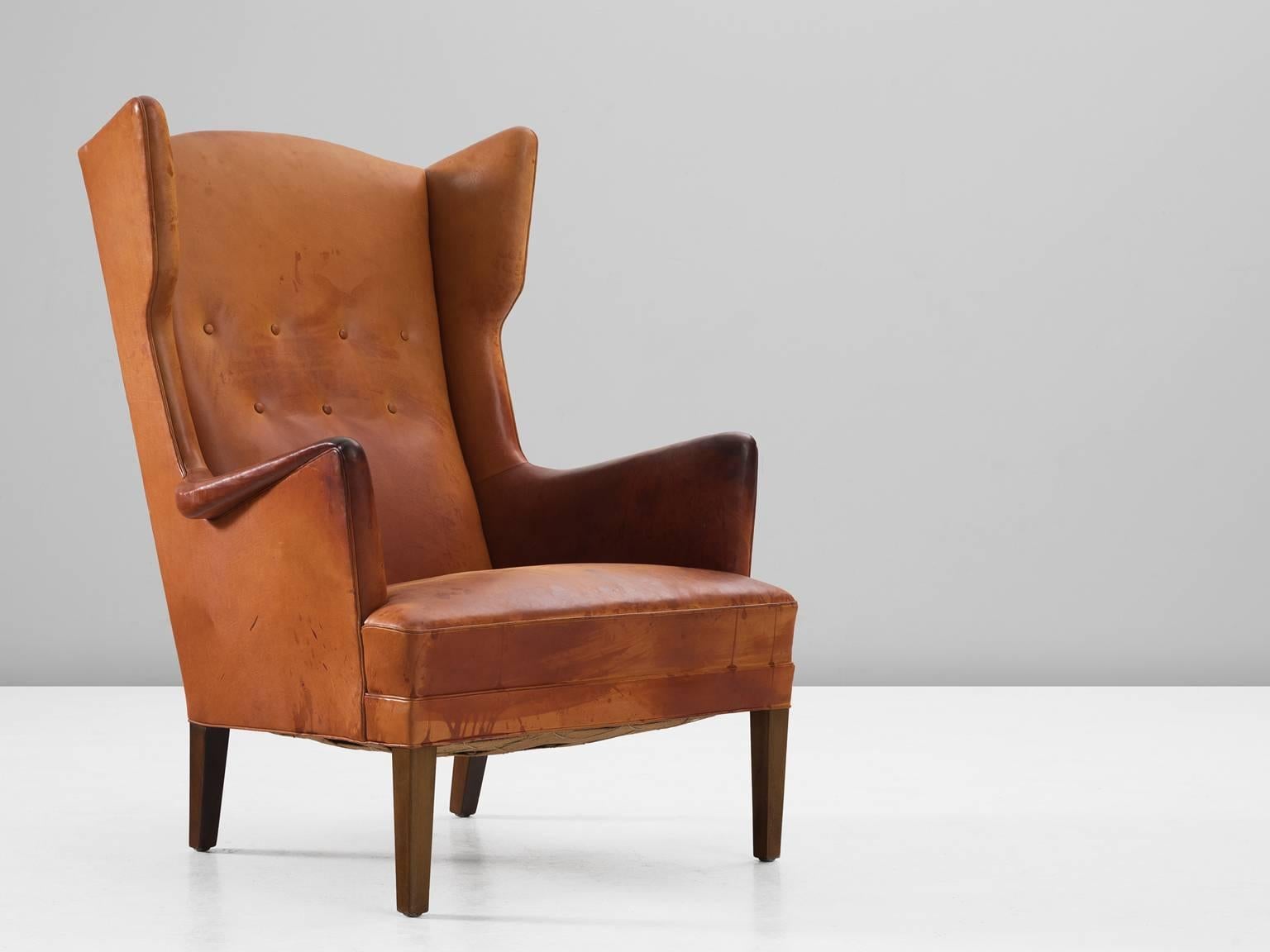 Lounge chair, in leather and wood, by Frits Henningsen, Denmark, 1950s. 

Rare wingback chair by Danish Designer Frits Henningsen. This chair shows the lines of a classical chair, yet combined with just enough modern details, to make it into a
