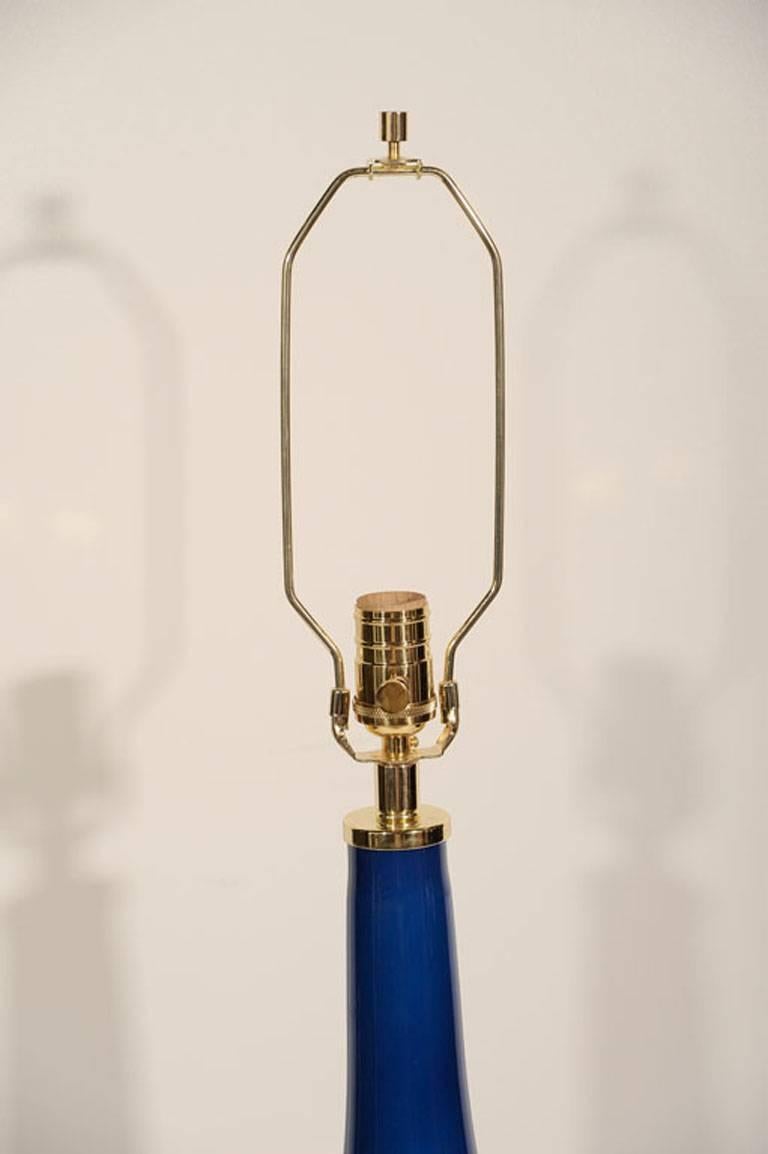Pair of cobalt blue glass lamps with two parallel 22-karat gold pinstripes. Lamps have been rewired for use in the USA with brass fittings. Shades not included.