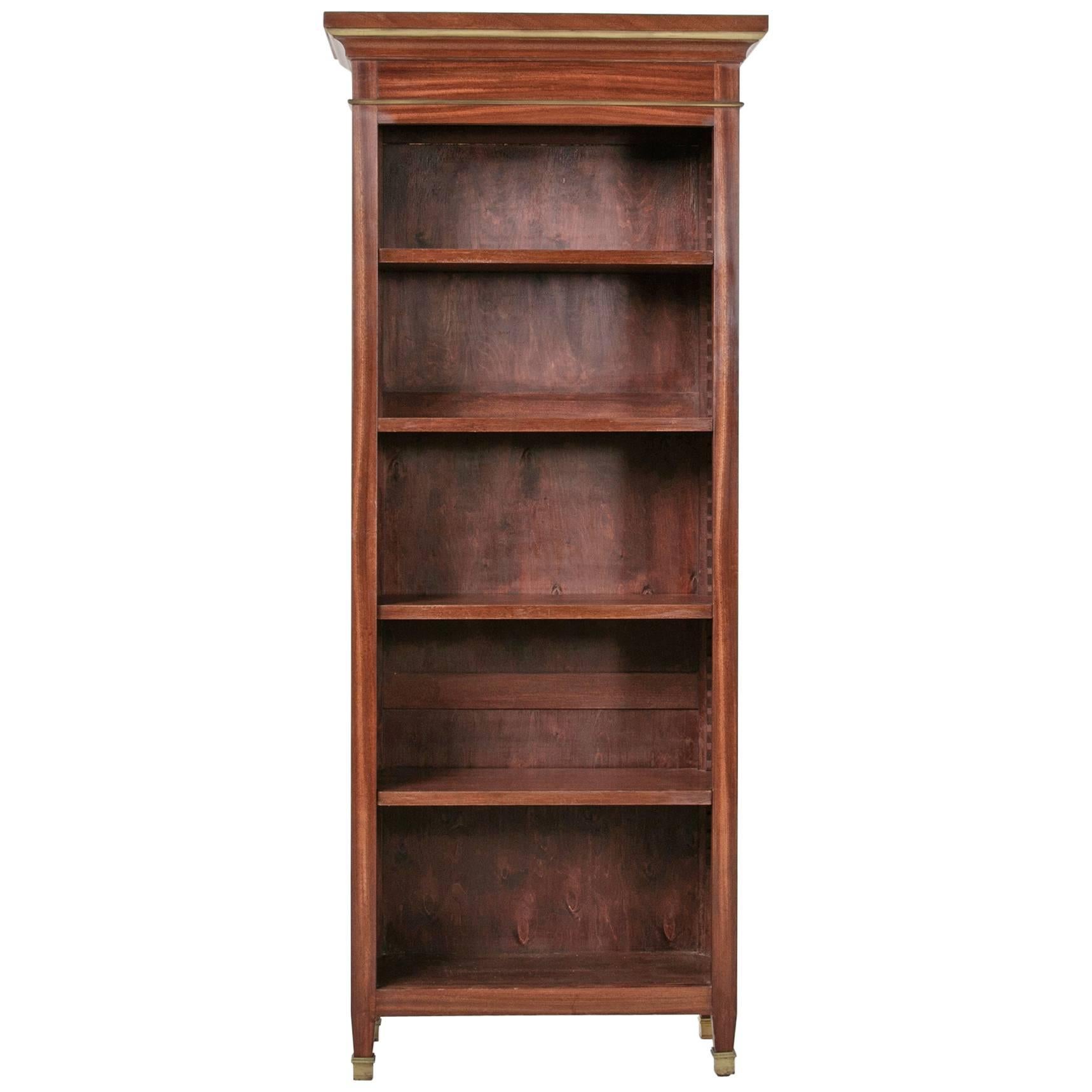 These mid-20th century Louis XVI style mahogany bookcases are finely detailed with bronze banding surrounding their recessed paneled sides and cornice. Their tapered legs are finished in bronze sabots. Four interior shelves, adjustable by means of