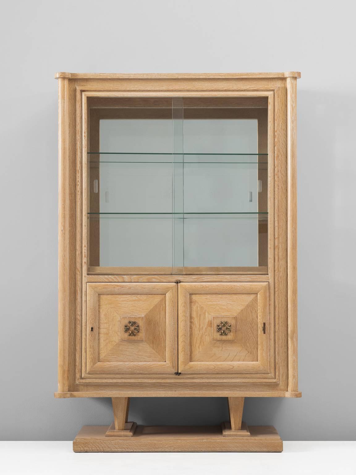 Cabinet, in glass and oak, France, 1940s. 

Nice detailed cabinet in oak and glass. The high storage part consist of a vitrine part, with two glass shelves and a mirrored back. The lower part is a cabinet with two doors. This cabinet was designed