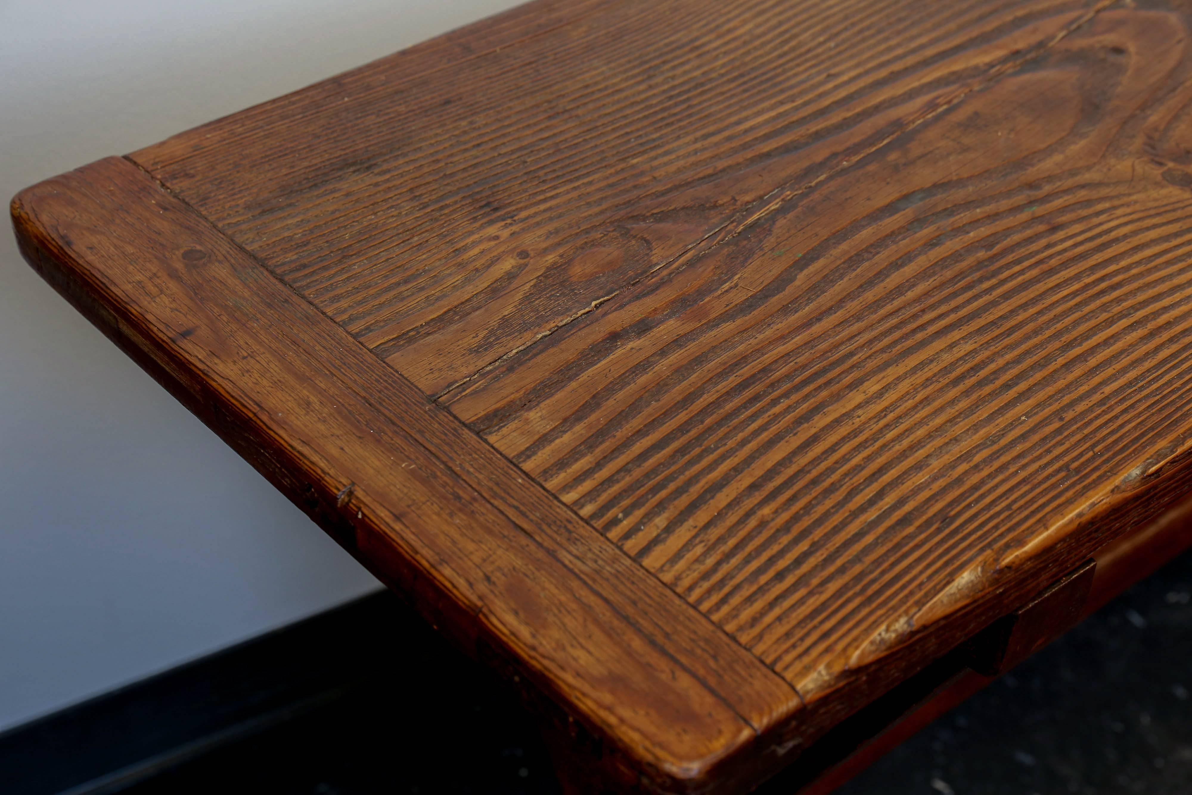 19th century English tavern table with a single plank top. Trestle base and breadboard detail on top. Grain has popped and produced a beautiful three dimensional look due to years of cleaning with a lye mixture. Very sturdy.