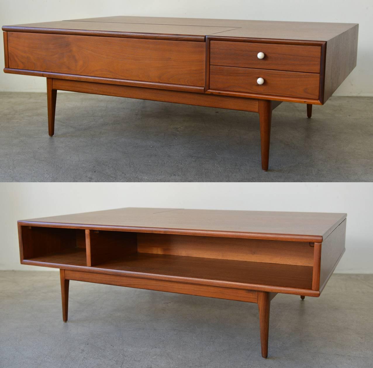 Beautiful Kipp Stewart Drexel Declaration coffee table.
This is made of beautiful rich walnut with a hidden interior storage and two drawers with the original round porcelain pulls. The opposite side has two open storage compartments. This table is