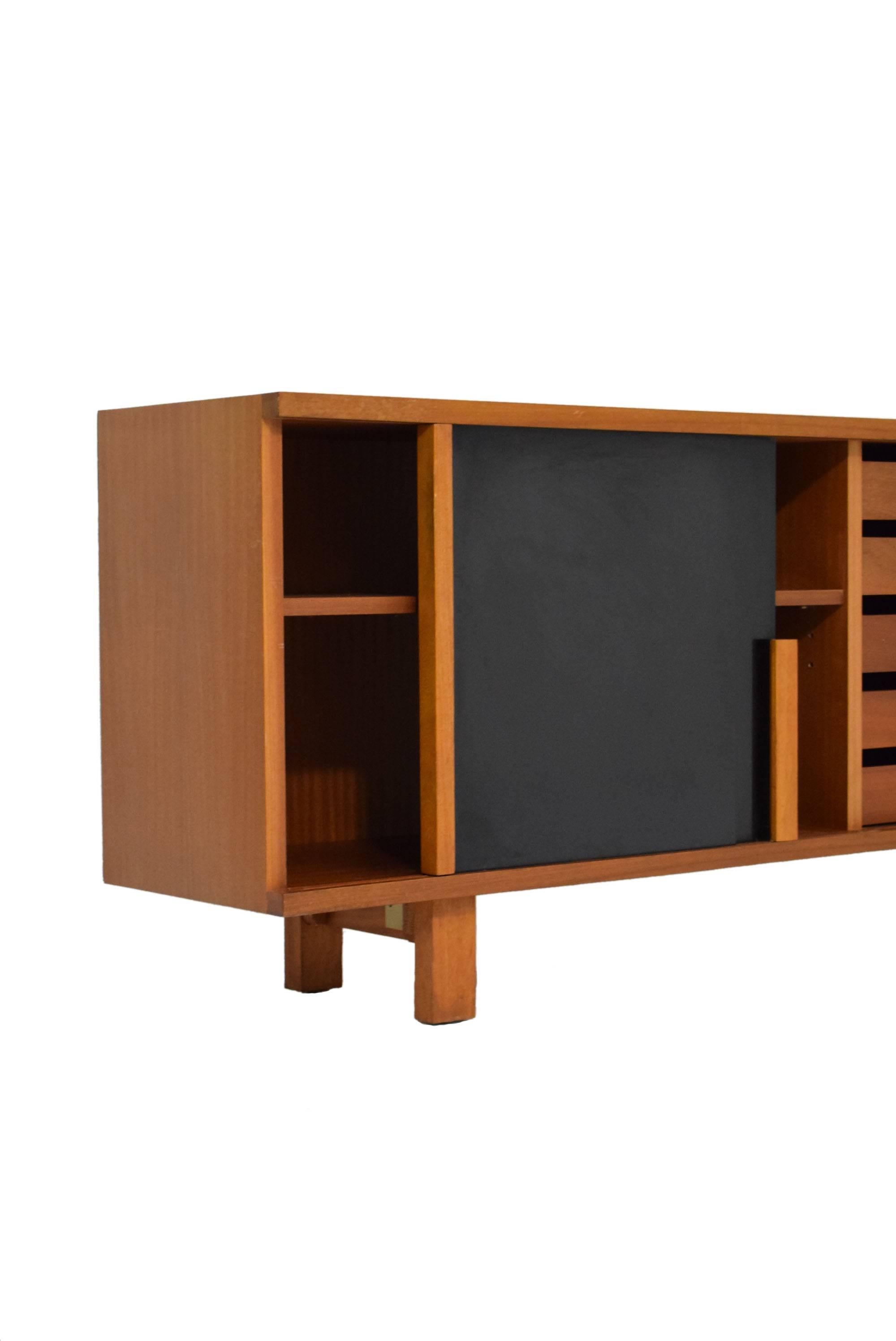 Rare 20th century sideboard in the manner of Charlotte Perriand.

Made from Sapele mahogany with original black lacquered sliding doors. 

Featuring stunning split handles, ten internal drawers and internal shelving. 

Superb 20th century design