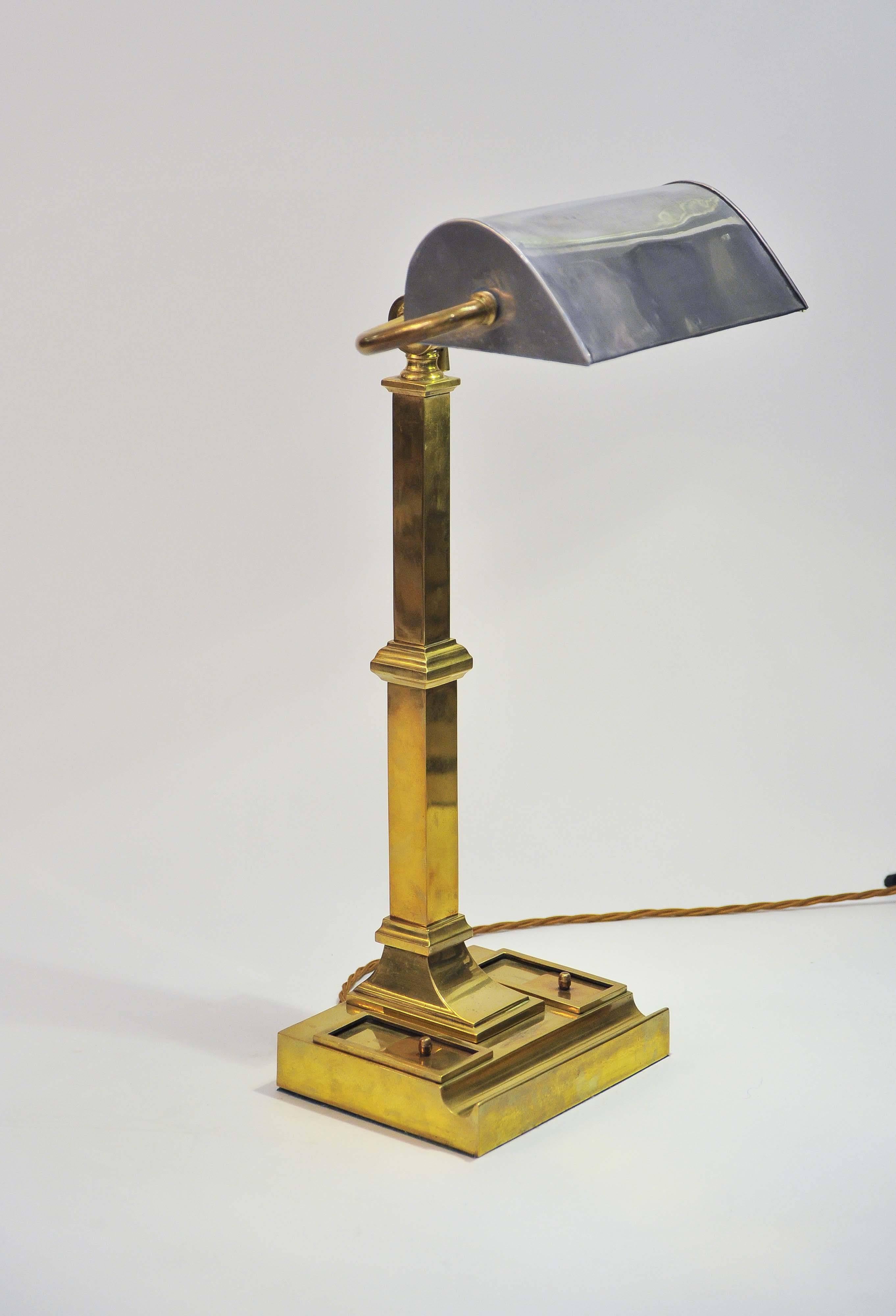 A fine early 20th century brass desk lamp with the original ceramic ink wells. The adjustable tin shade probably replacing a green glass shade in 1940s.