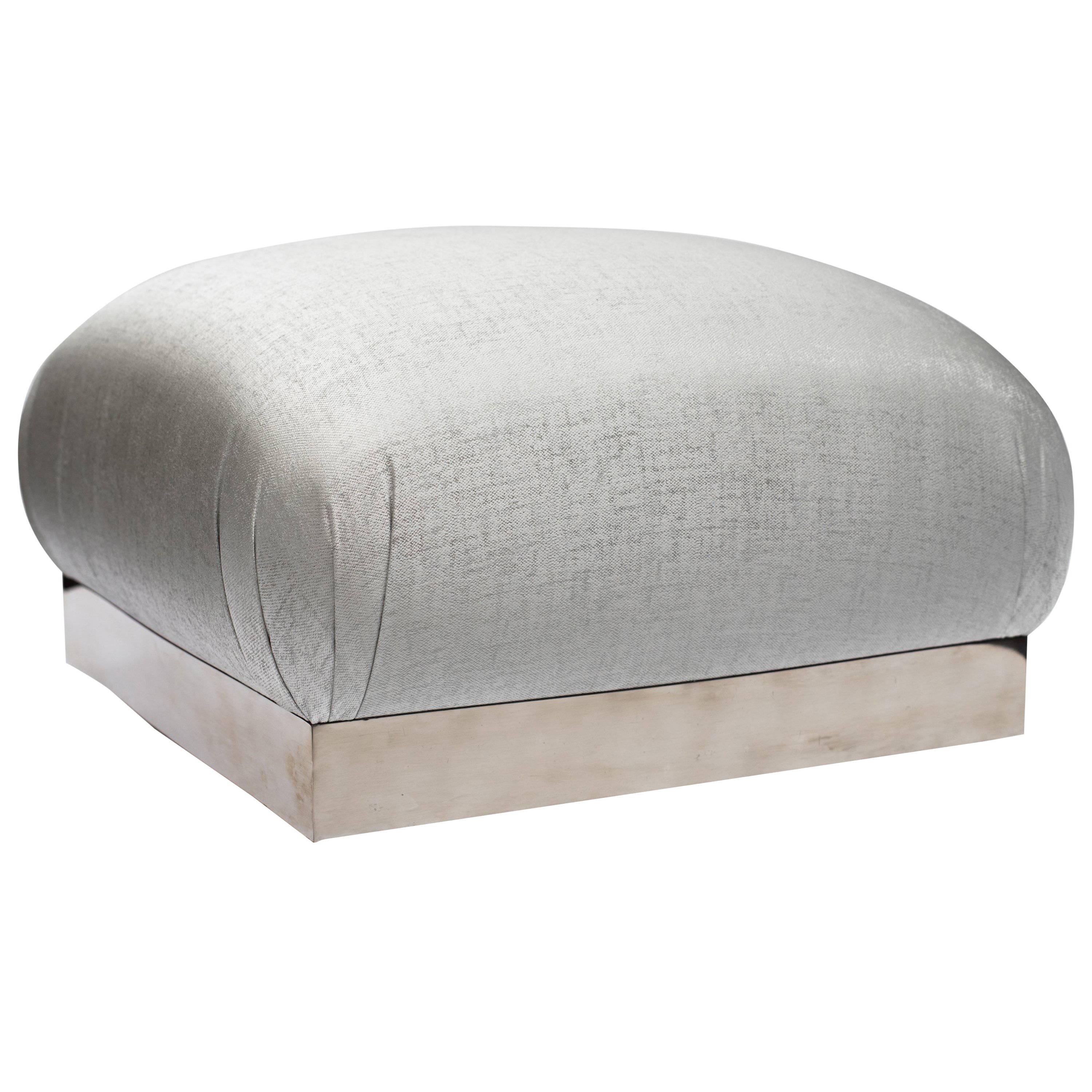 Elegant mid-century modern ottoman with iconic soufflé design and oversized features. Pouf has large square cushion with rounded edges and chrome banded base fitted with swivel casters. Newly upholstered in woven platinum mist (silver tones with sea